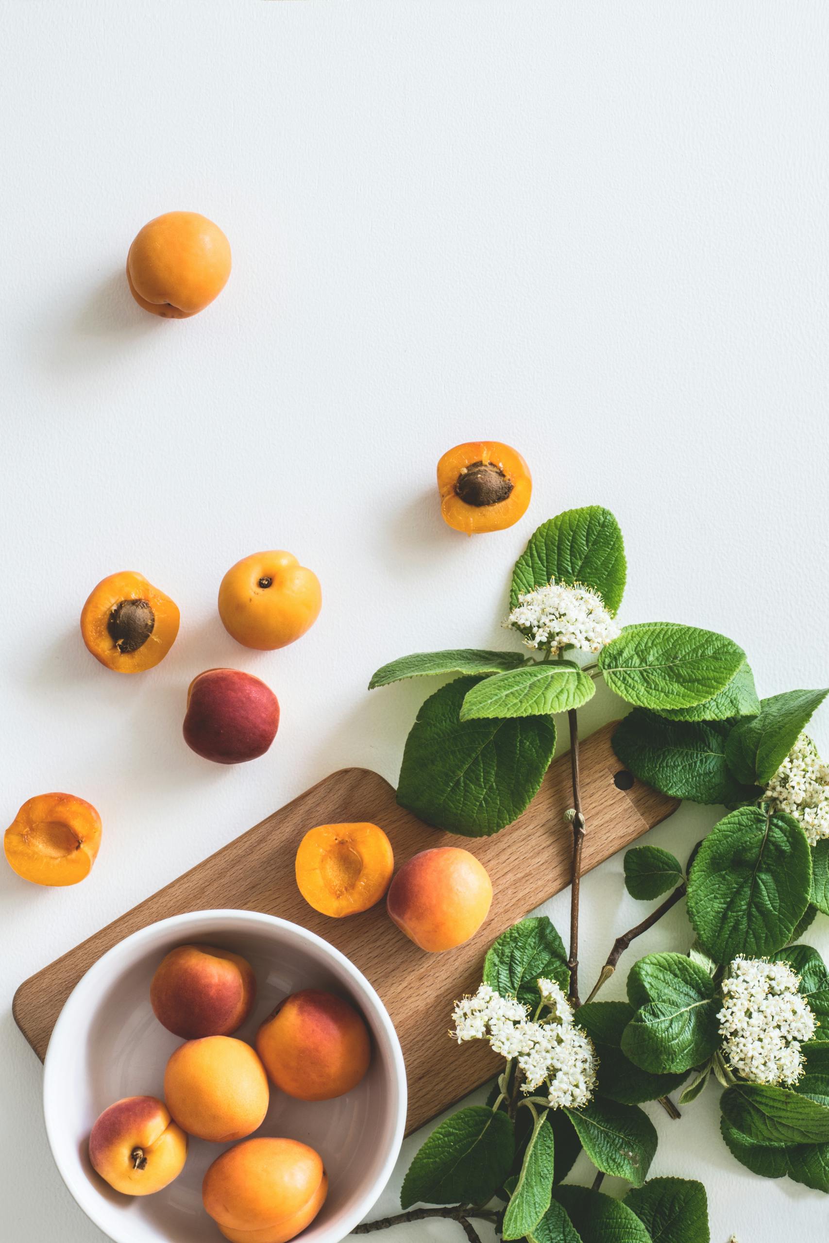 starvation mode: A flat lay of fresh apricots and blossoms on a board showcasing summer freshness.