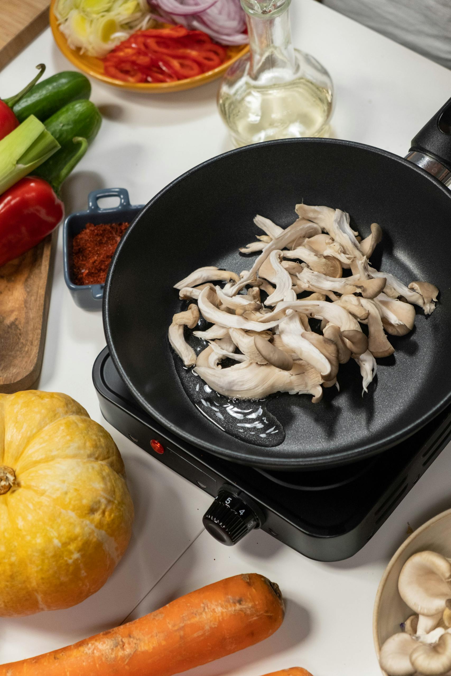 tips for vegetarians: Overhead shot of fresh mushrooms frying on an electric stove with vegetables.