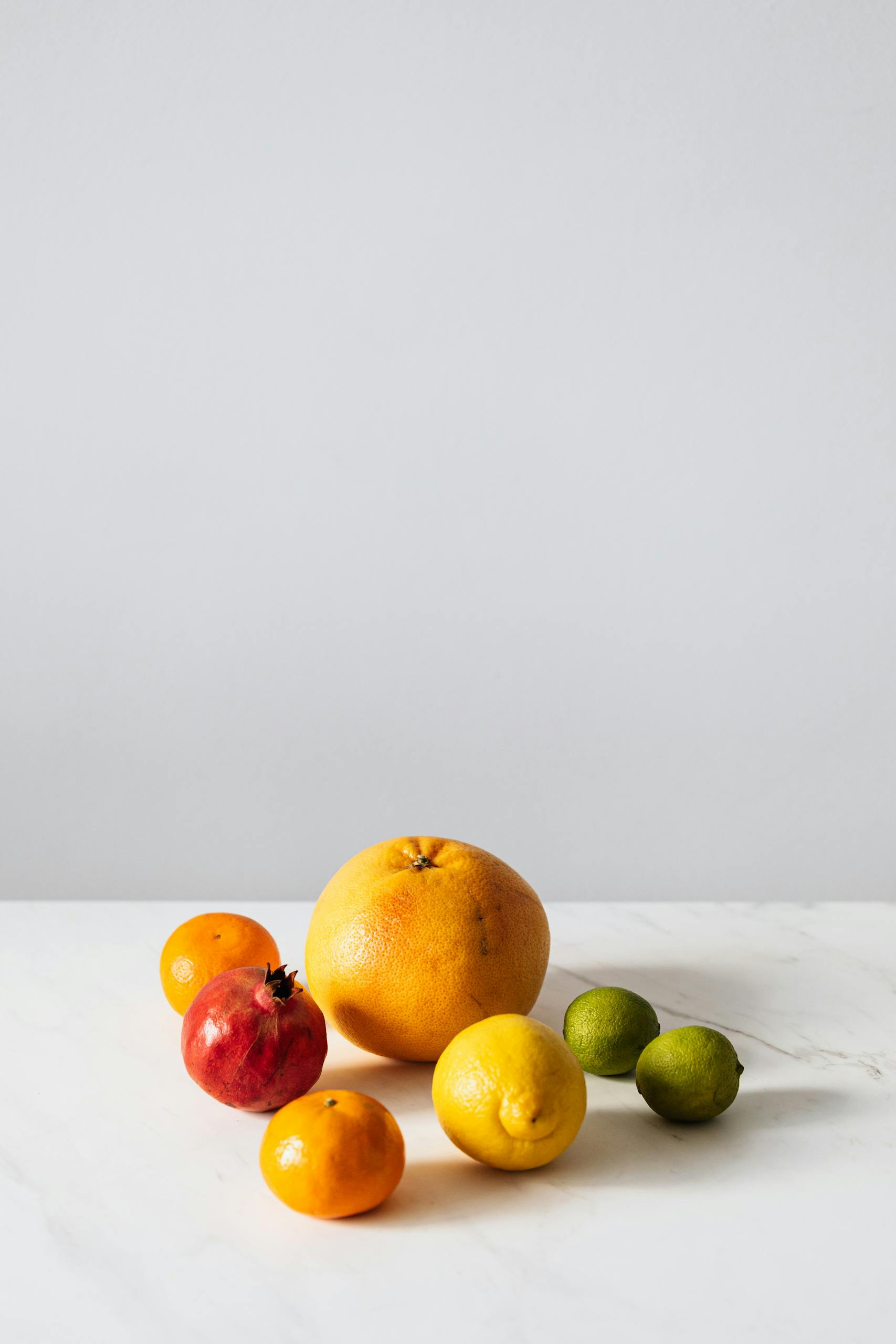 healthy eating hacks: A vibrant assortment of citrus fruits and pomegranate on a white surface with copy space.