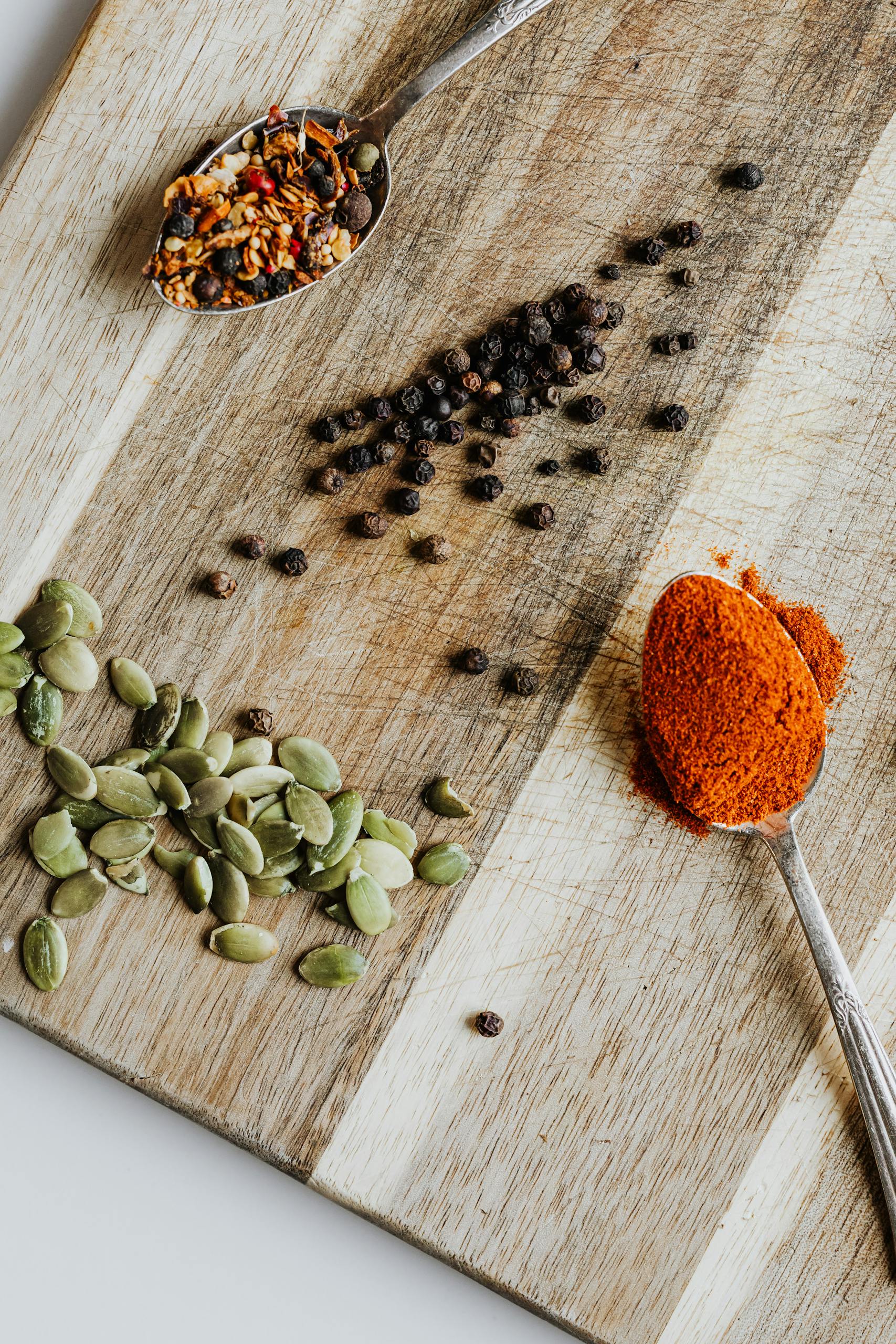 high-protein snacks: Assorted spices and seeds on a wooden board, featuring vibrant colors and textures.