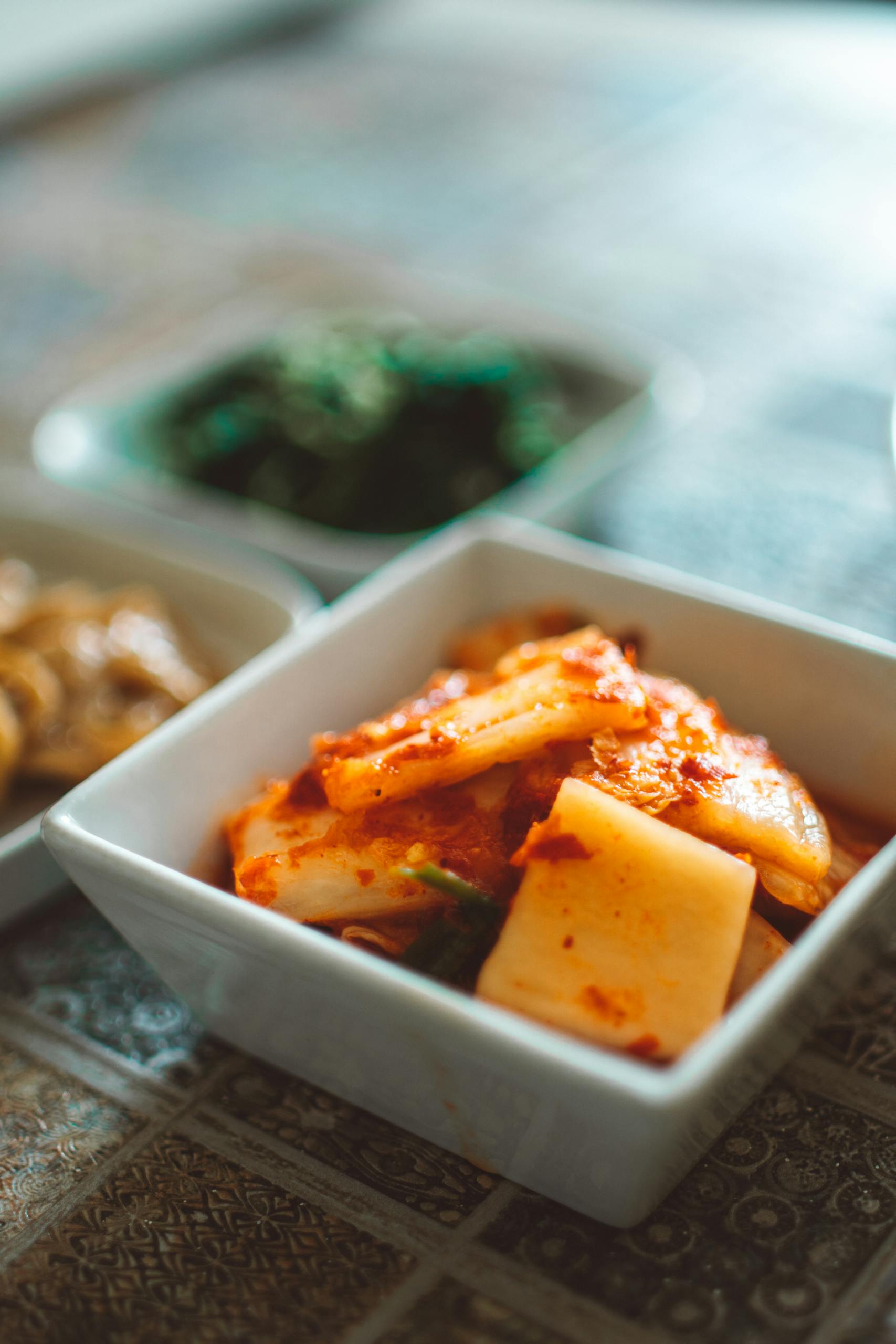 Foods That Help With PMS Symptoms: Close-up of spicy Korean kimchi in a ceramic bowl, showcasing traditional flavors and vibrant colors.