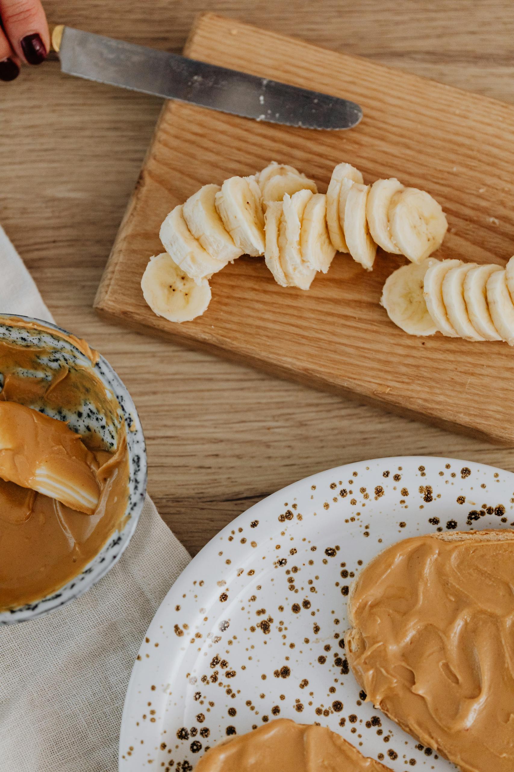 best healthy snacks at whole foods market: Delicious slices of banana paired with creamy peanut butter on a wooden board.