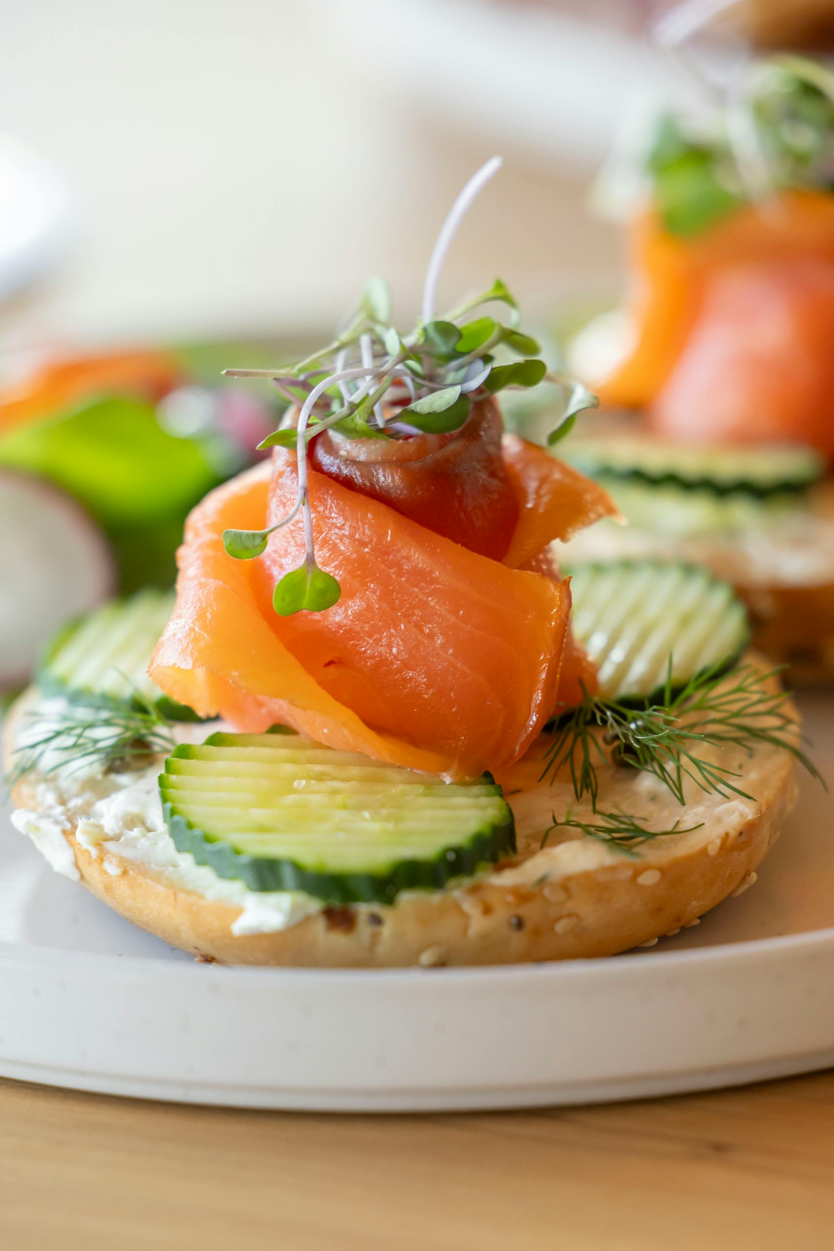 fad diets to avoid: Tasty smoked salmon bagel with cucumbers, cream cheese, dill, and microgreens, served on a plate.
