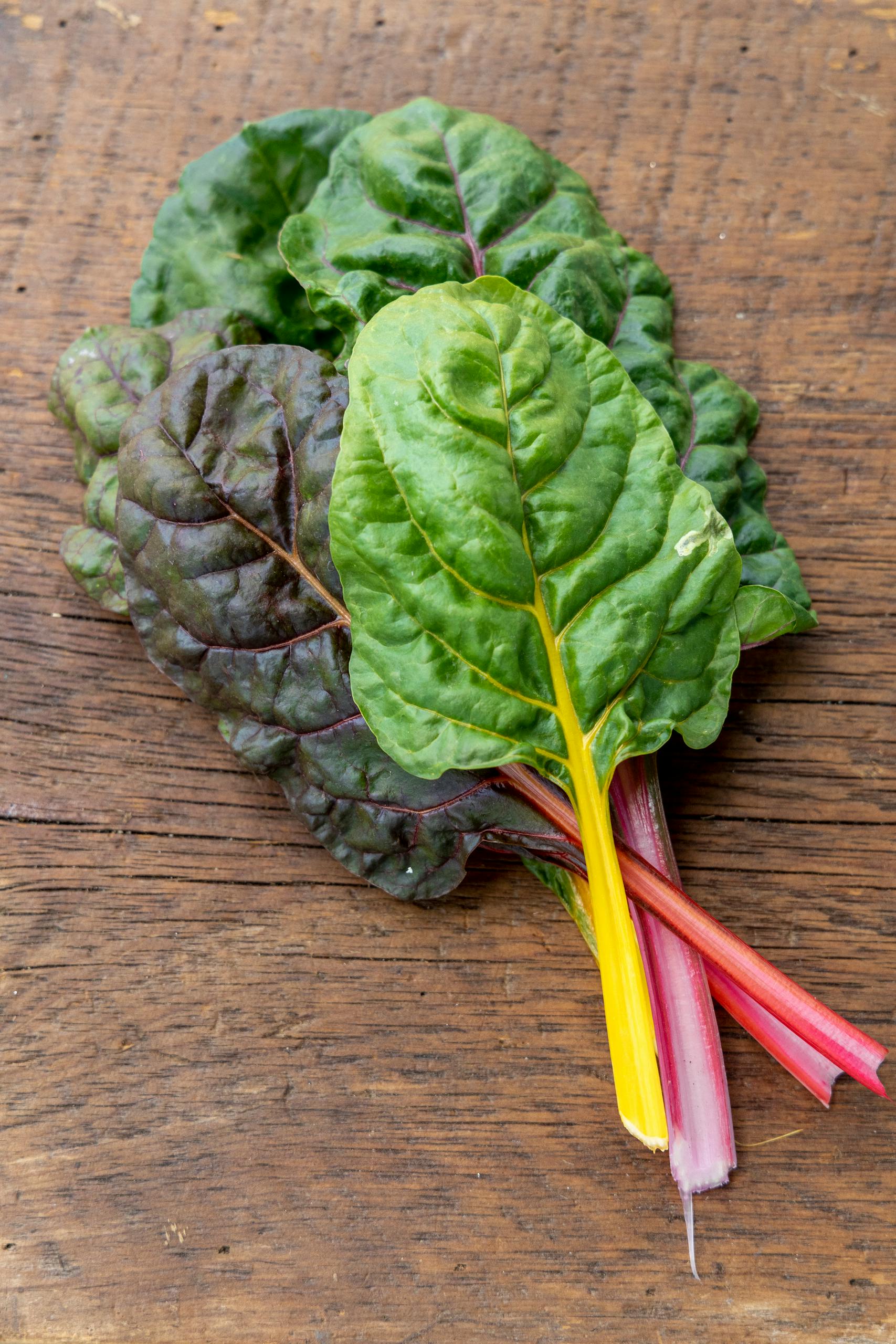 Swiss chard benefits: Vibrant fresh Swiss chard leaves with colorful stalks on a rustic wooden table.