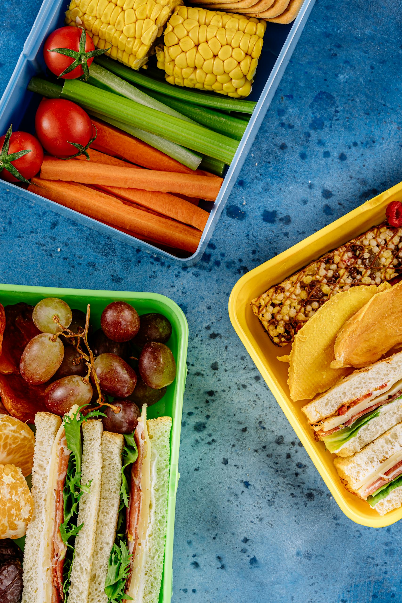 Body recomposition meal plan for beginners: A vibrant flat lay of healthy lunch boxes featuring sandwiches, fruits, and vegetables, perfect for a nutritious meal.