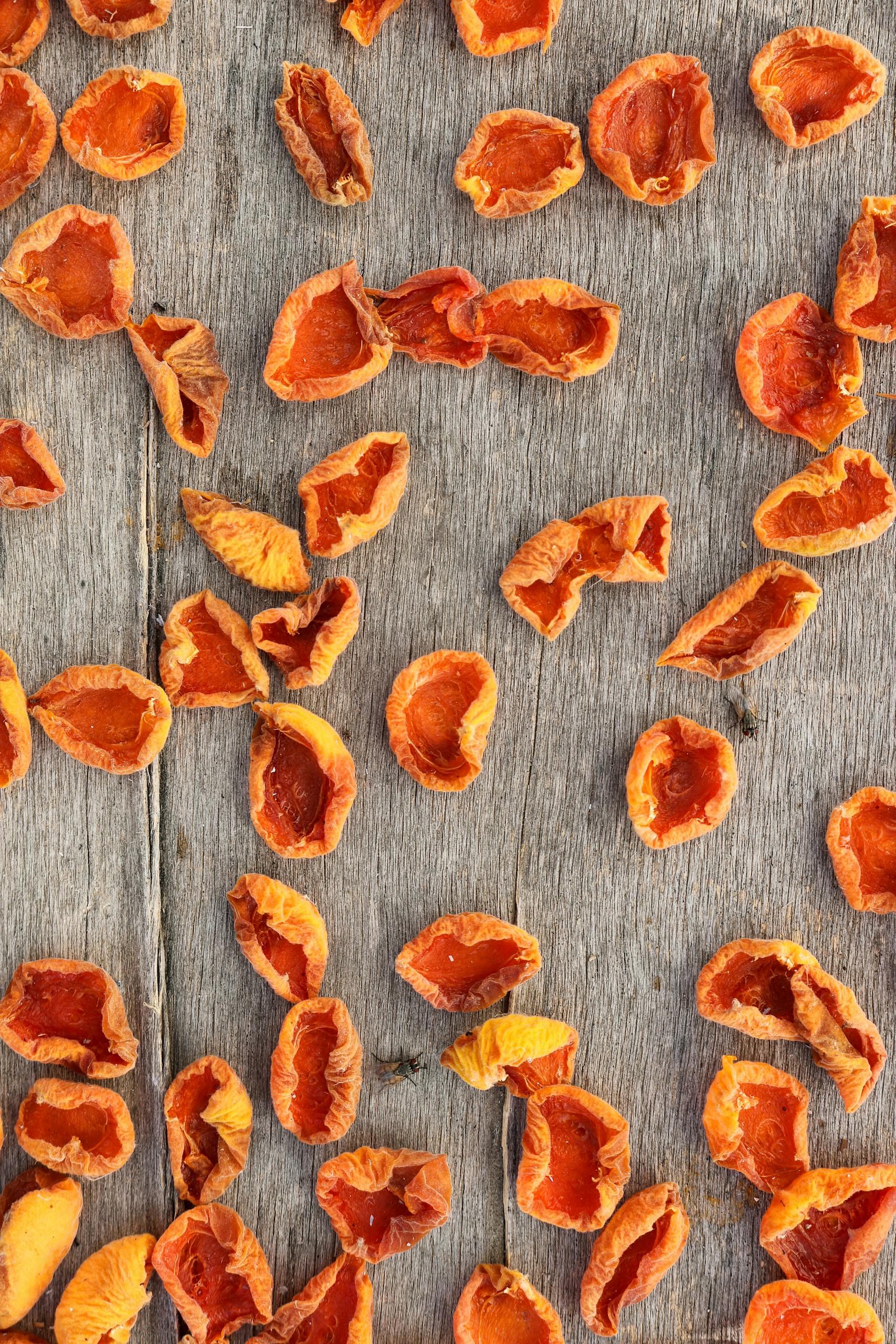 top plant-based iron foods: Close-up of dried apricot halves scattered on a rustic wooden surface, creating a vibrant and natural texture.