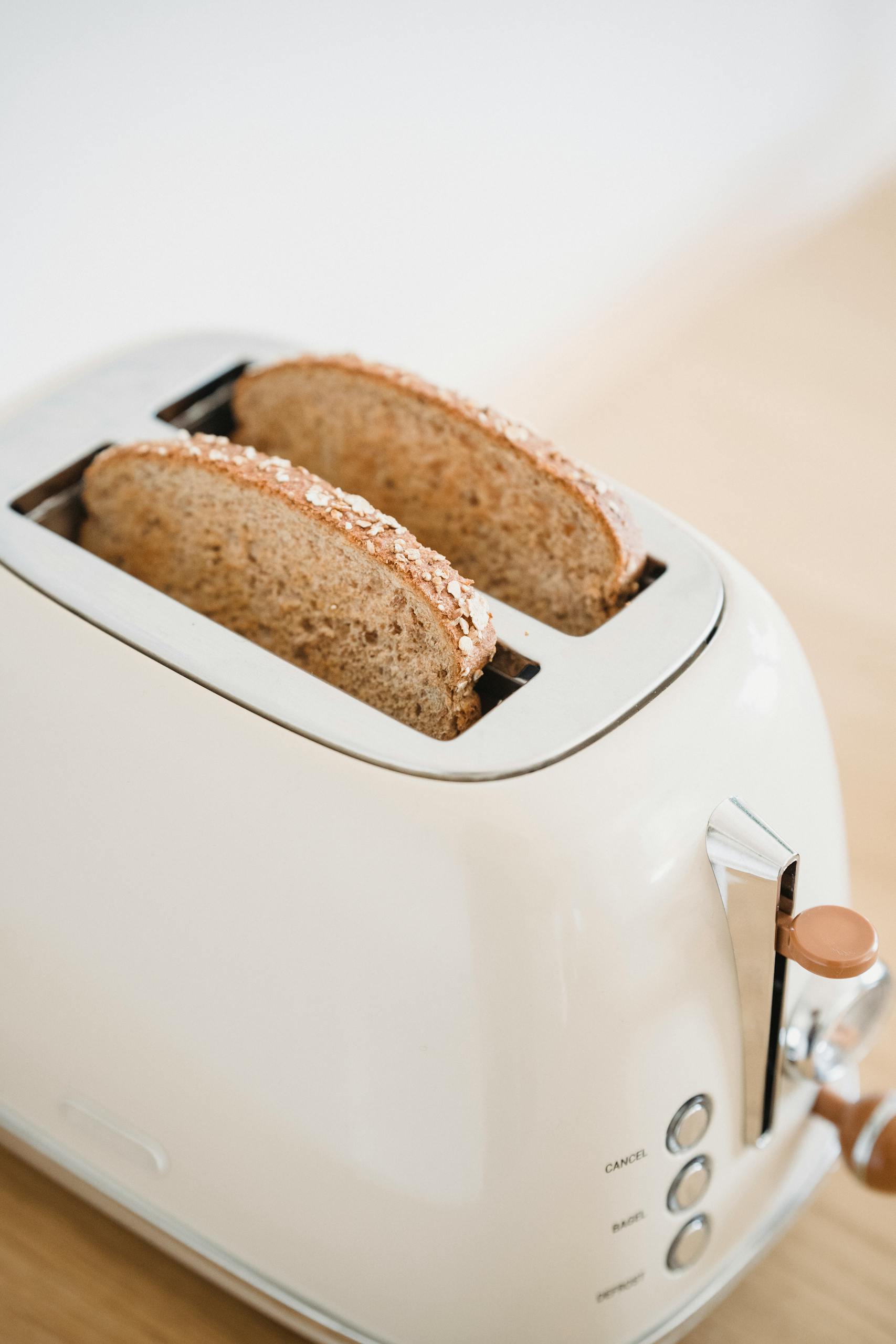foods to eat for nausea on GLP-1: Close-up of whole grain bread slices in a vintage toaster, perfect for breakfast themes.