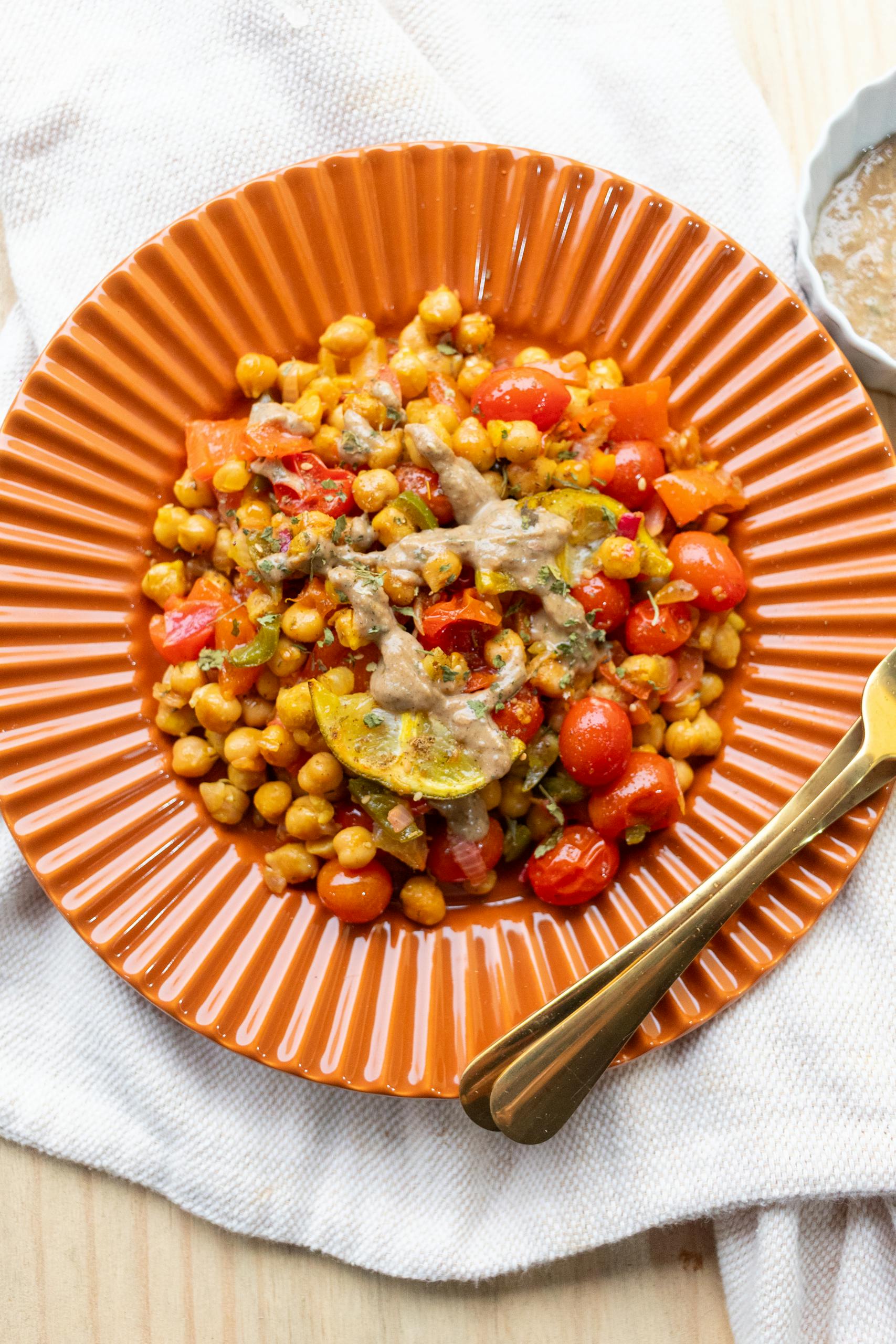 not losing weight on GLP-1: Colorful chickpea and roasted vegetable salad on an orange plate, perfect for a healthy meal.