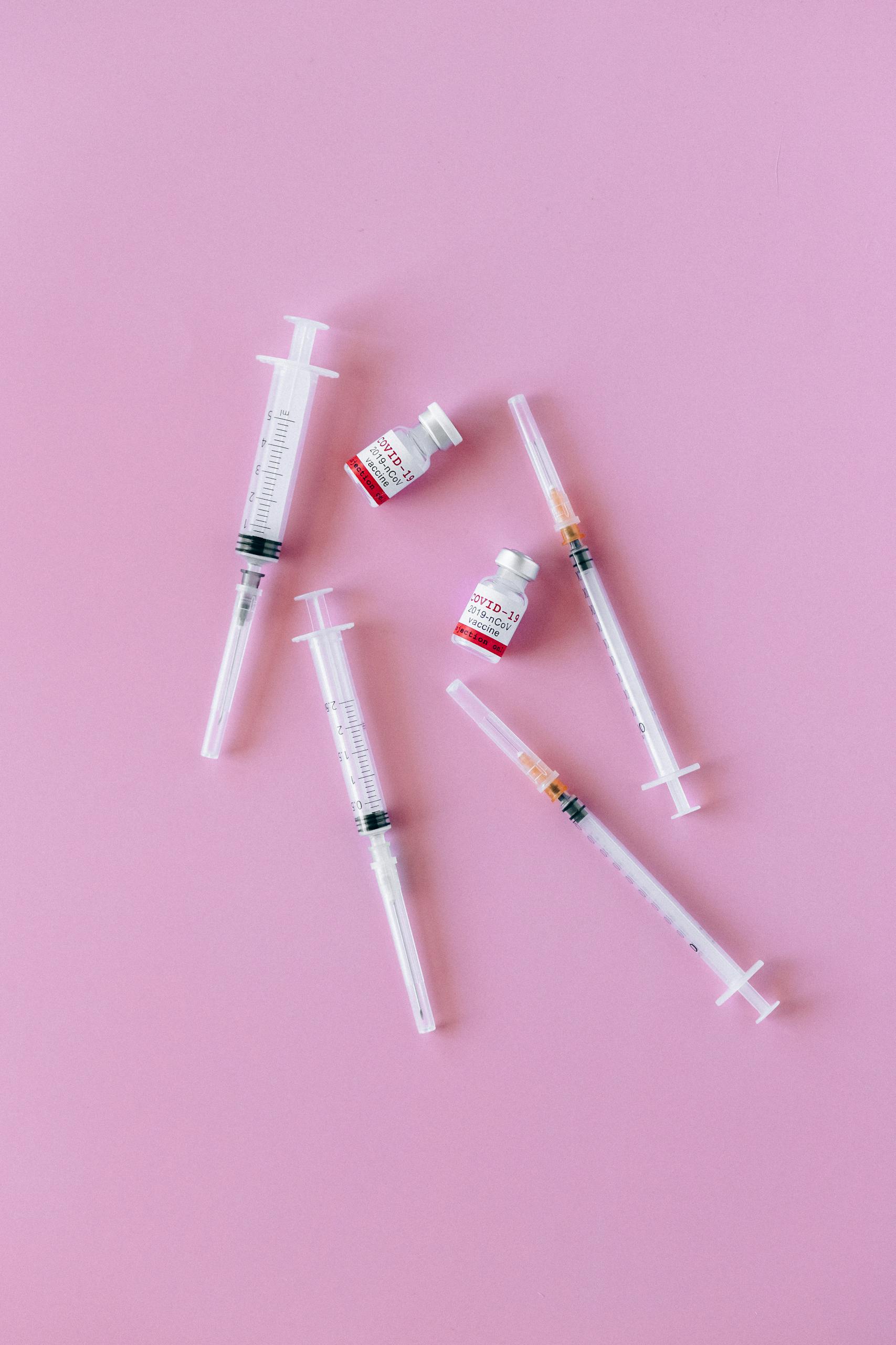 not losing weight on glp-1: Syringes and vials arranged on a pink background for medical and healthcare concepts.