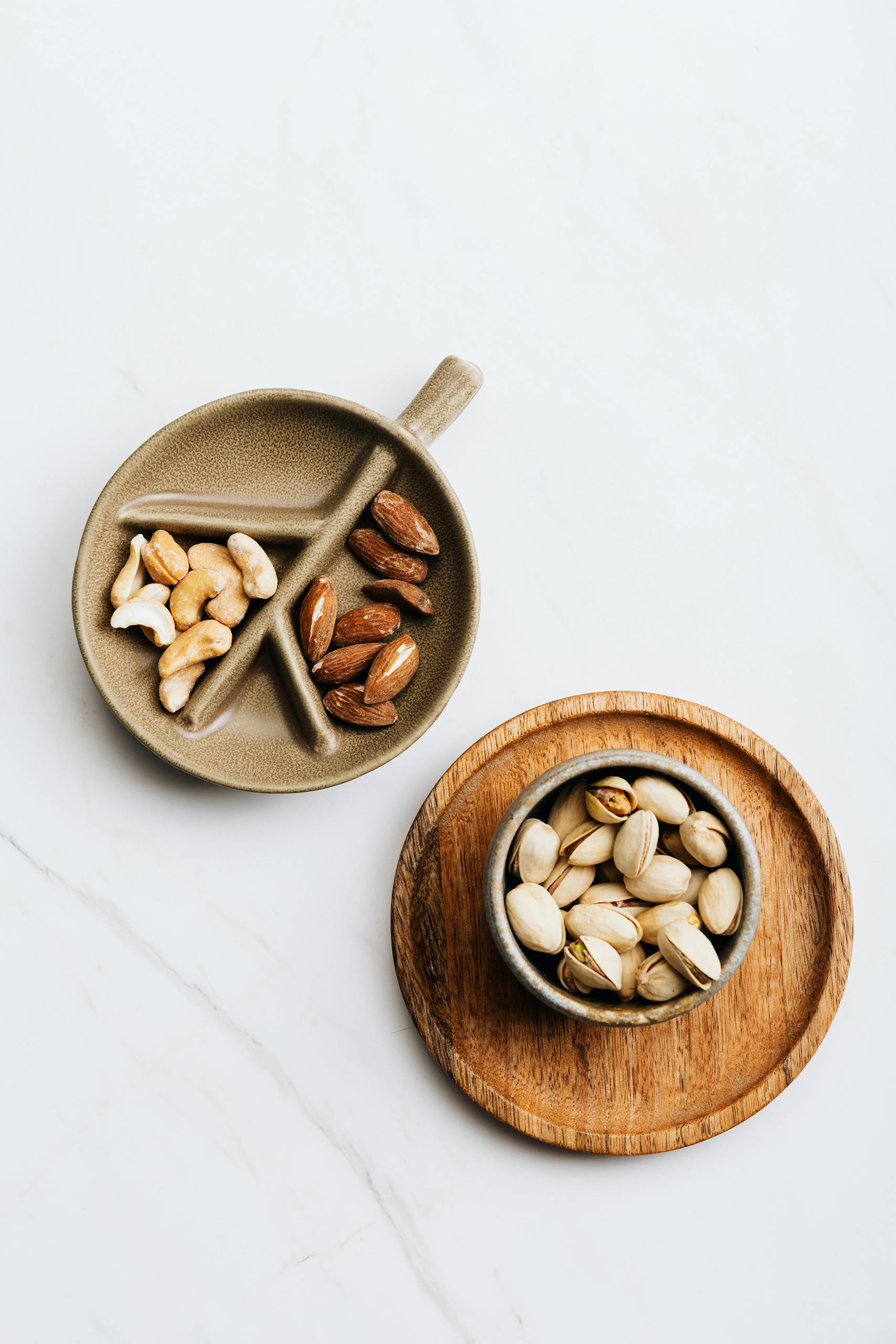 is snacking bad for metabolism: Top view of various nuts in rustic ceramic bowls on a white background with copy space.