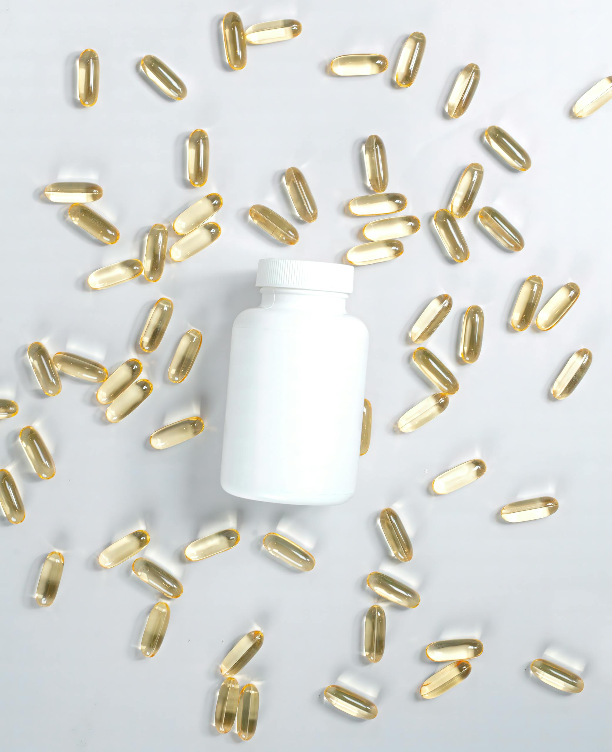 do you need vitamin D supplements: A flat lay of a supplement bottle surrounded by oil capsules on a white surface.