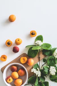 starvation mode: A flat lay of fresh apricots and blossoms on a board showcasing summer freshness.
