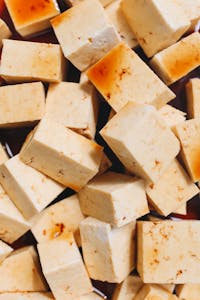 benefits of tofu: Appetizing close-up of tofu cubes soaked in savory soy sauce, capturing rich textures and flavors.