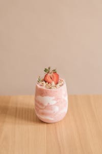 kefir benefits: Delicious strawberry smoothie with granola topping in a glass on a wooden table.