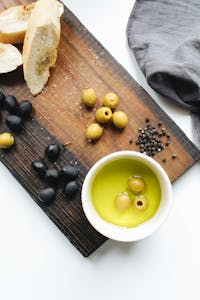 healthy fats: Rustic wooden board with fresh olives, bread, and olive oil. Perfect for culinary themes.