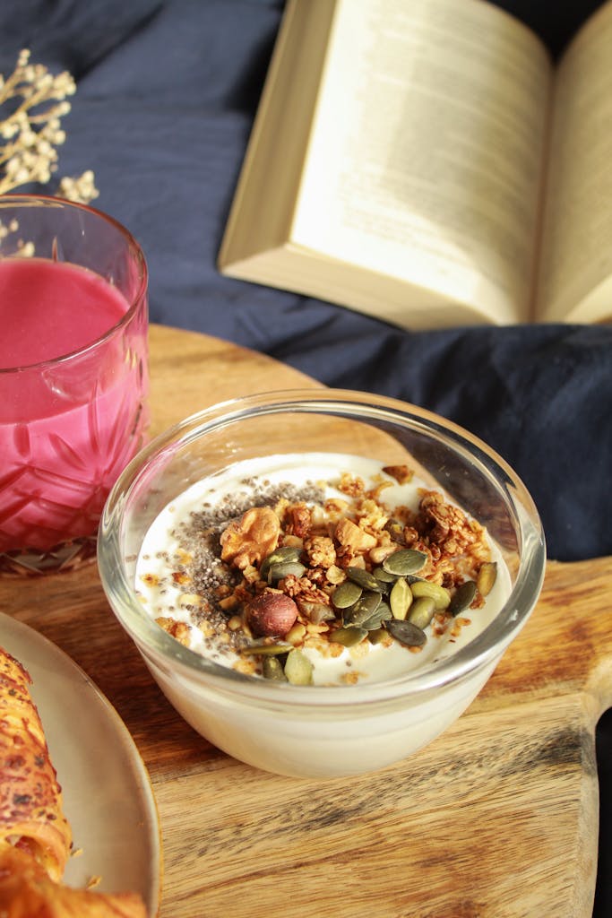 30 grams of fiber a day: A cozy setup with yogurt, nuts, juice, and an open book on a wooden surface.