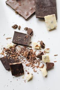easy ways to add magnesium-rich foods to your diet: A delicious assortment of broken chocolate pieces on a white background with a focus on dark and white chocolate.
