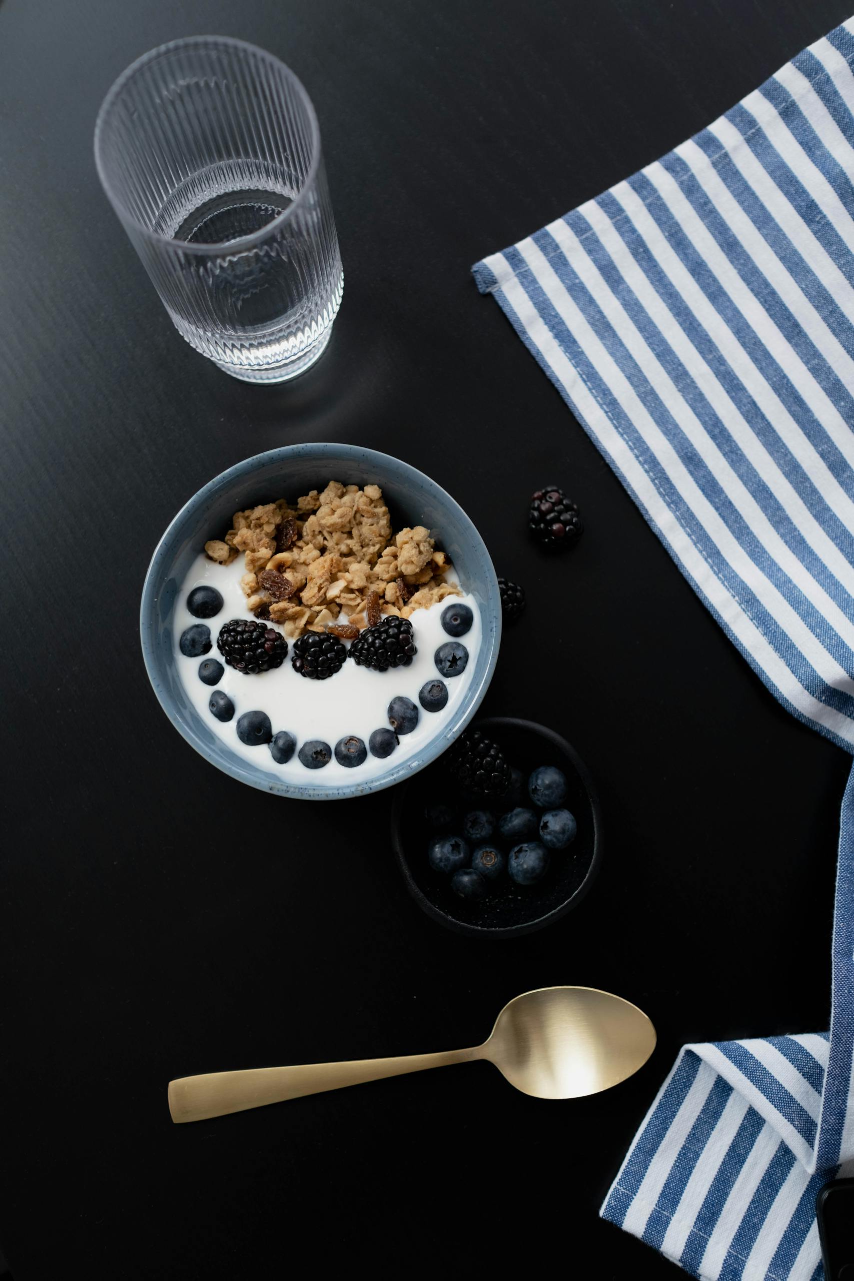 best probiotics for digestion: A healthy breakfast bowl with granola, blackberries, and blueberries on a dark surface.