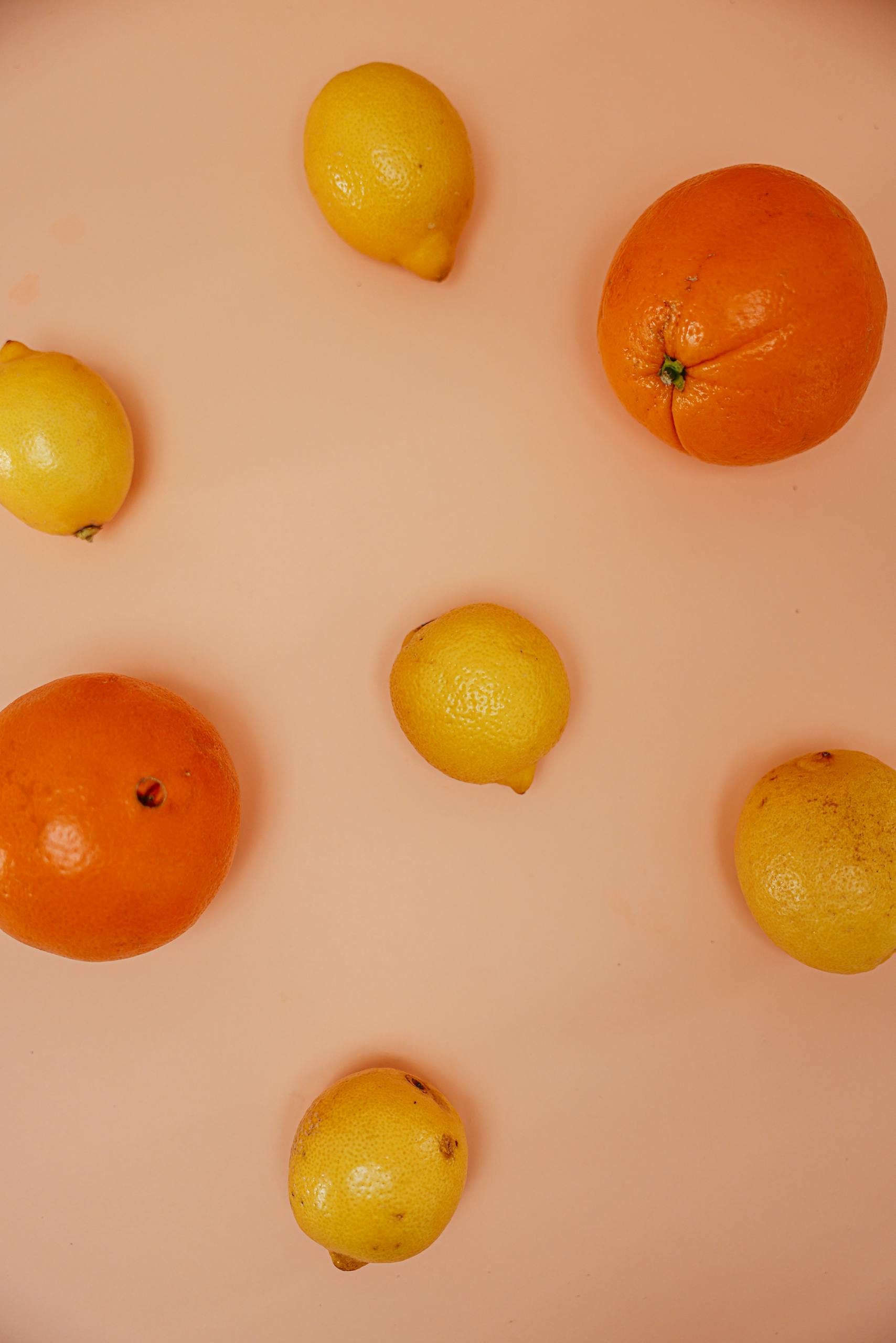 perimenopause nutrition: A vibrant arrangement of citrus fruits including oranges and lemons on a pink surface.