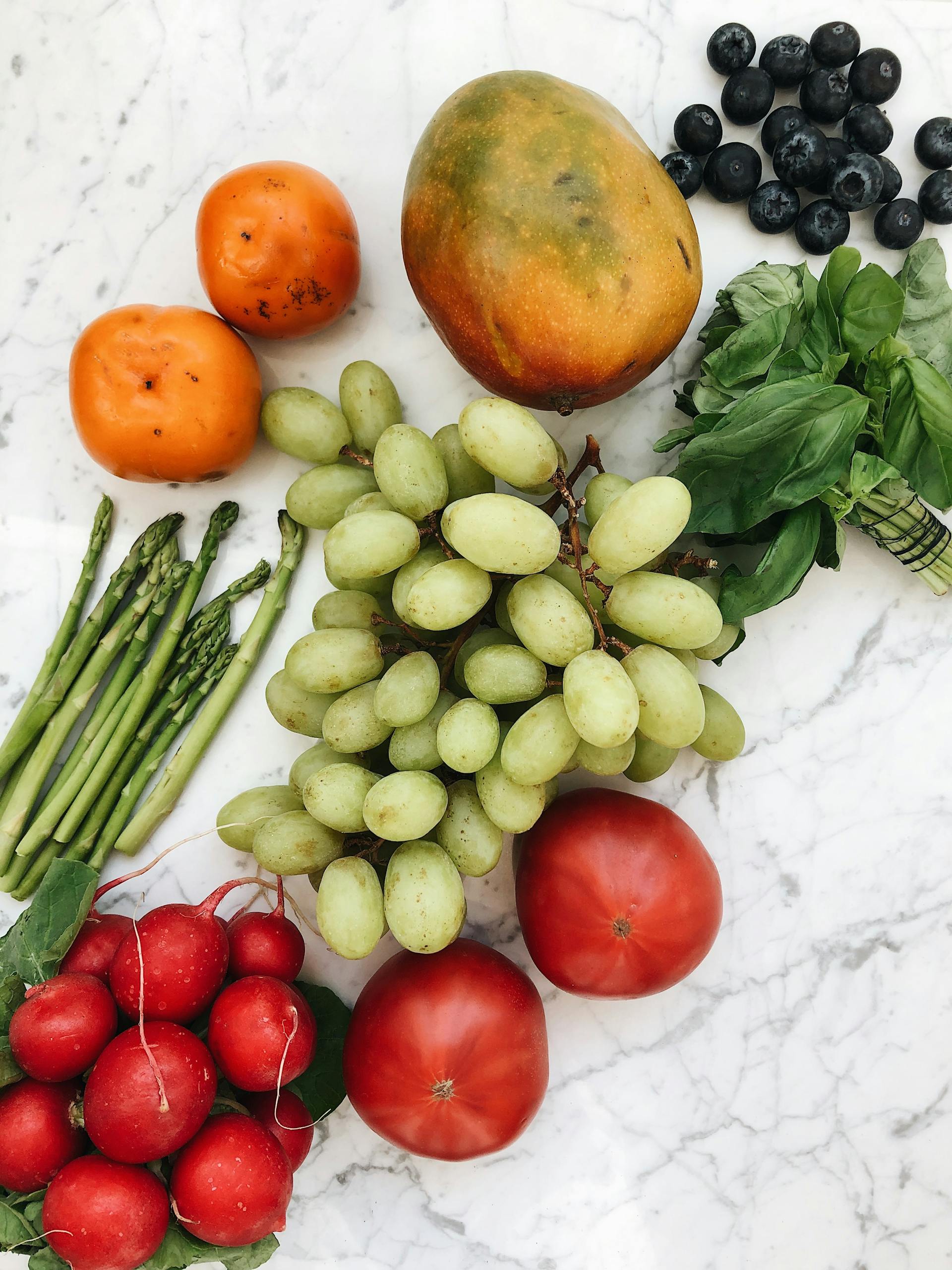 Nutrition Habits for Brain Health: A vibrant flat lay of fresh fruits and vegetables on a marble surface, showcasing healthy food options.