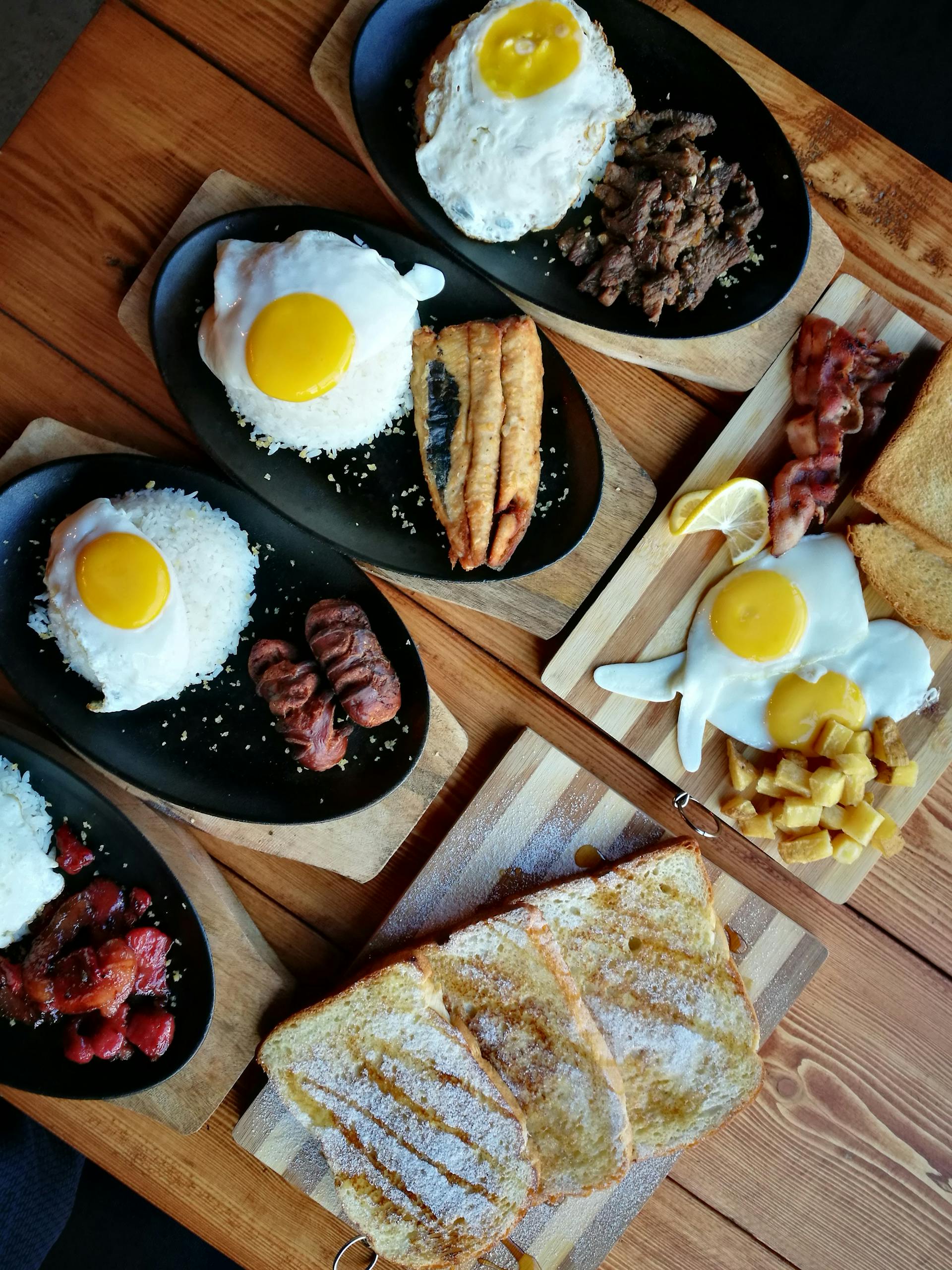 fad diets to avoid: An appetizing breakfast spread featuring eggs, meats, toast, and rice on a wooden table.