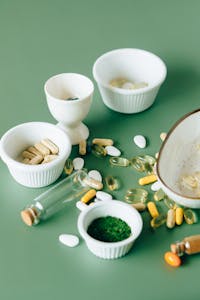 best supplements for brain health: Assorted natural supplements and pills in ceramic bowls on a green background, showcasing health and wellness themes.