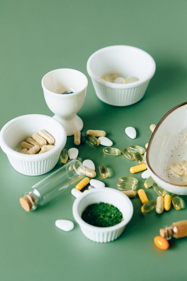 best supplements for brain health: Assorted natural supplements and pills in ceramic bowls on a green background, showcasing health and wellness themes.
