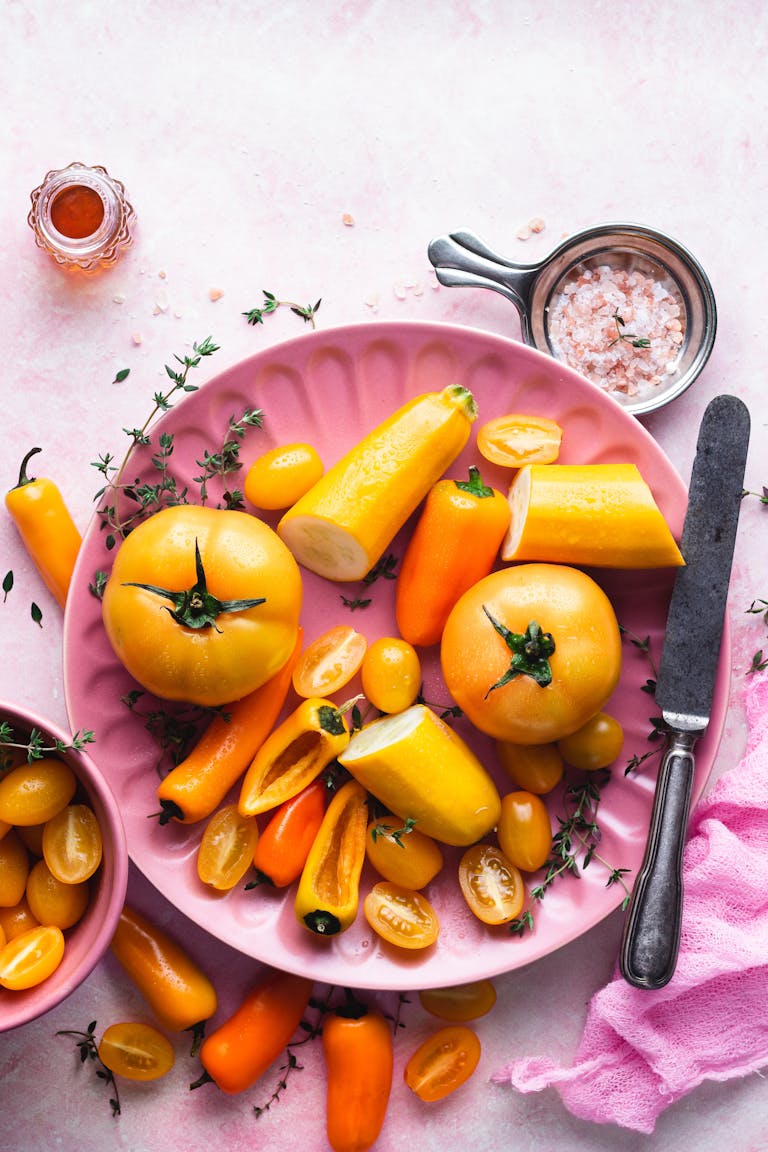 Sneak More Vegetables Into Meals: Bright composition of yellow tomatoes and peppers on a pink plate with seasoning.