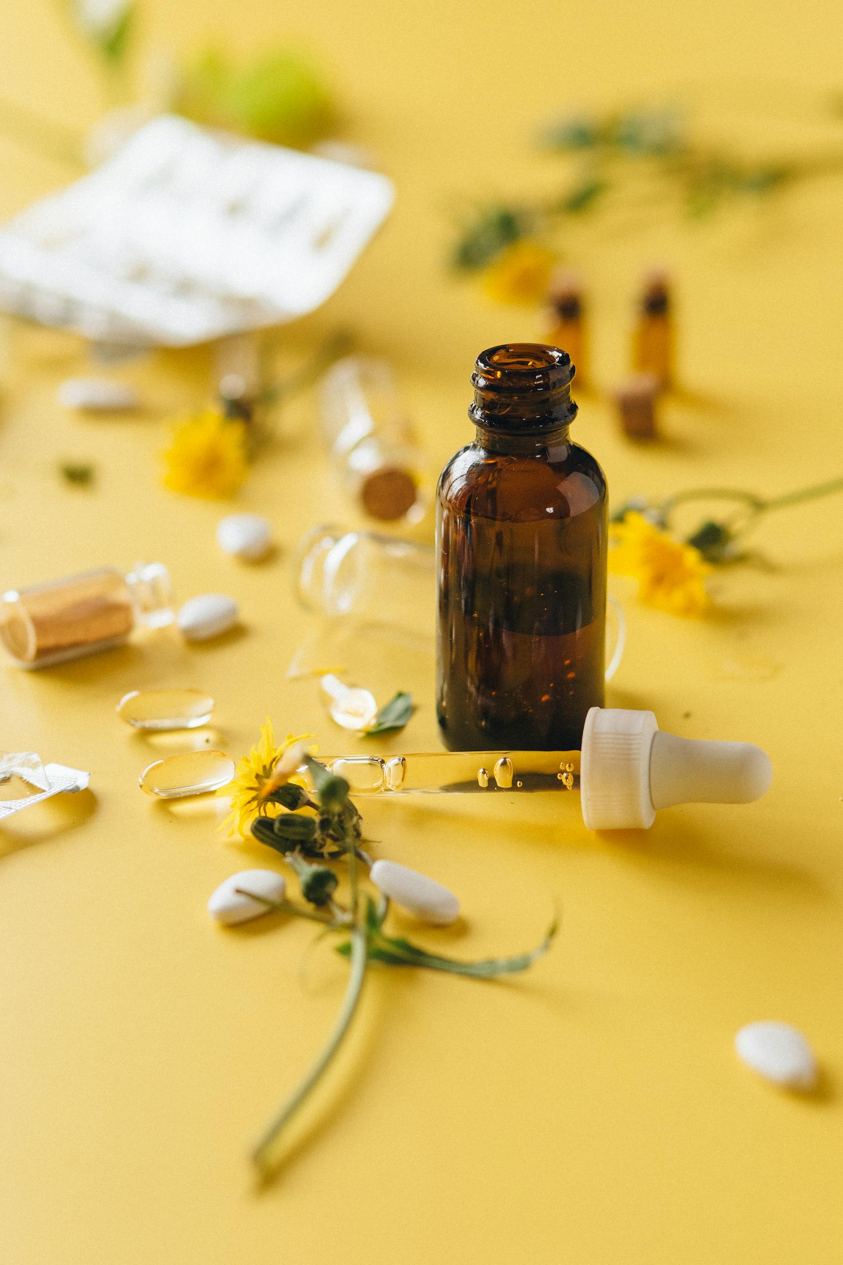 best supplements for brain health: Brown glass dropper bottle among herbs and pills on yellow surface, ideal for wellness themes.