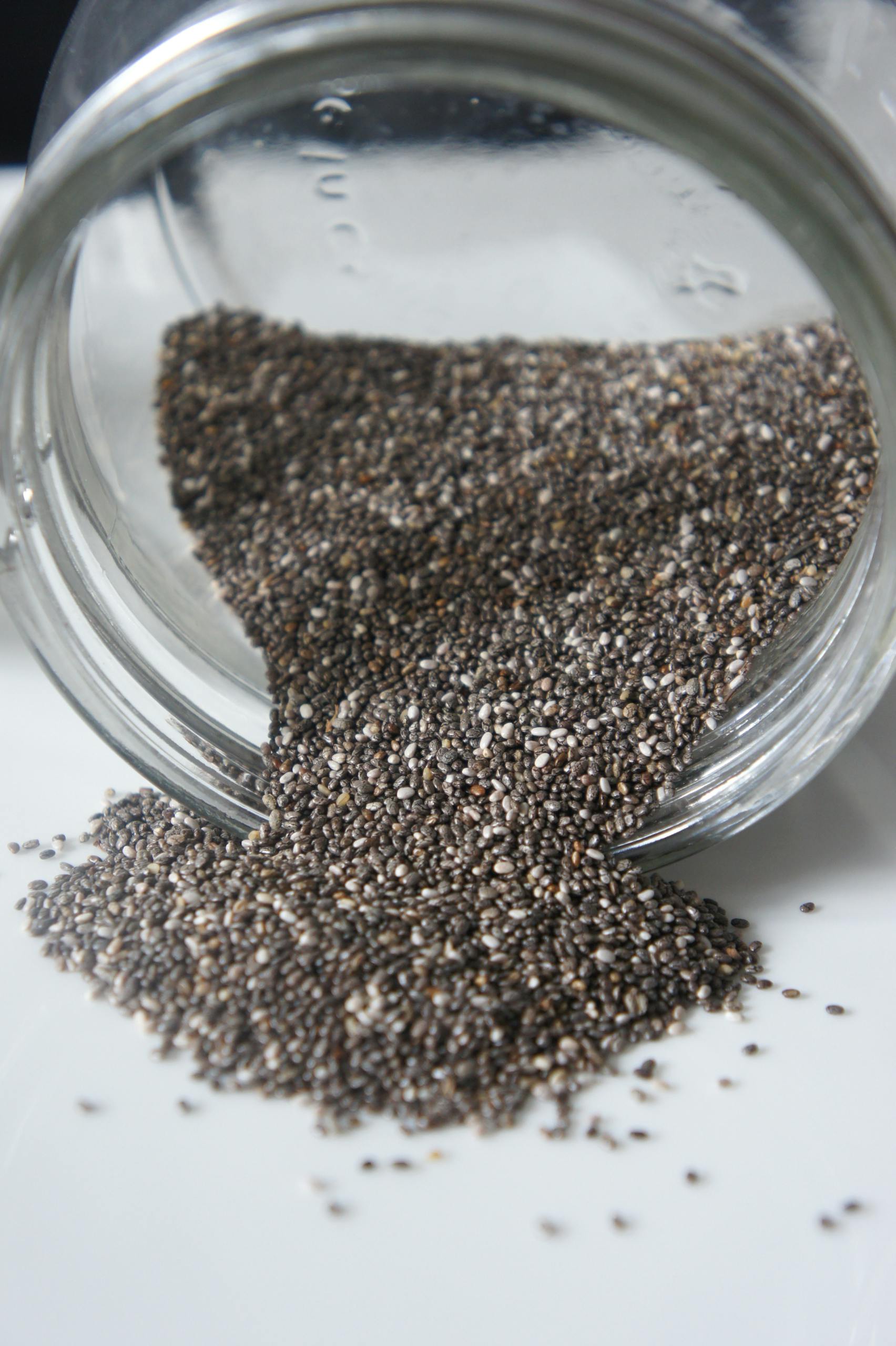 chia seeds for gut health benefits: Chia seeds pouring out from a glass jar, perfect for healthy lifestyle or food blogs.