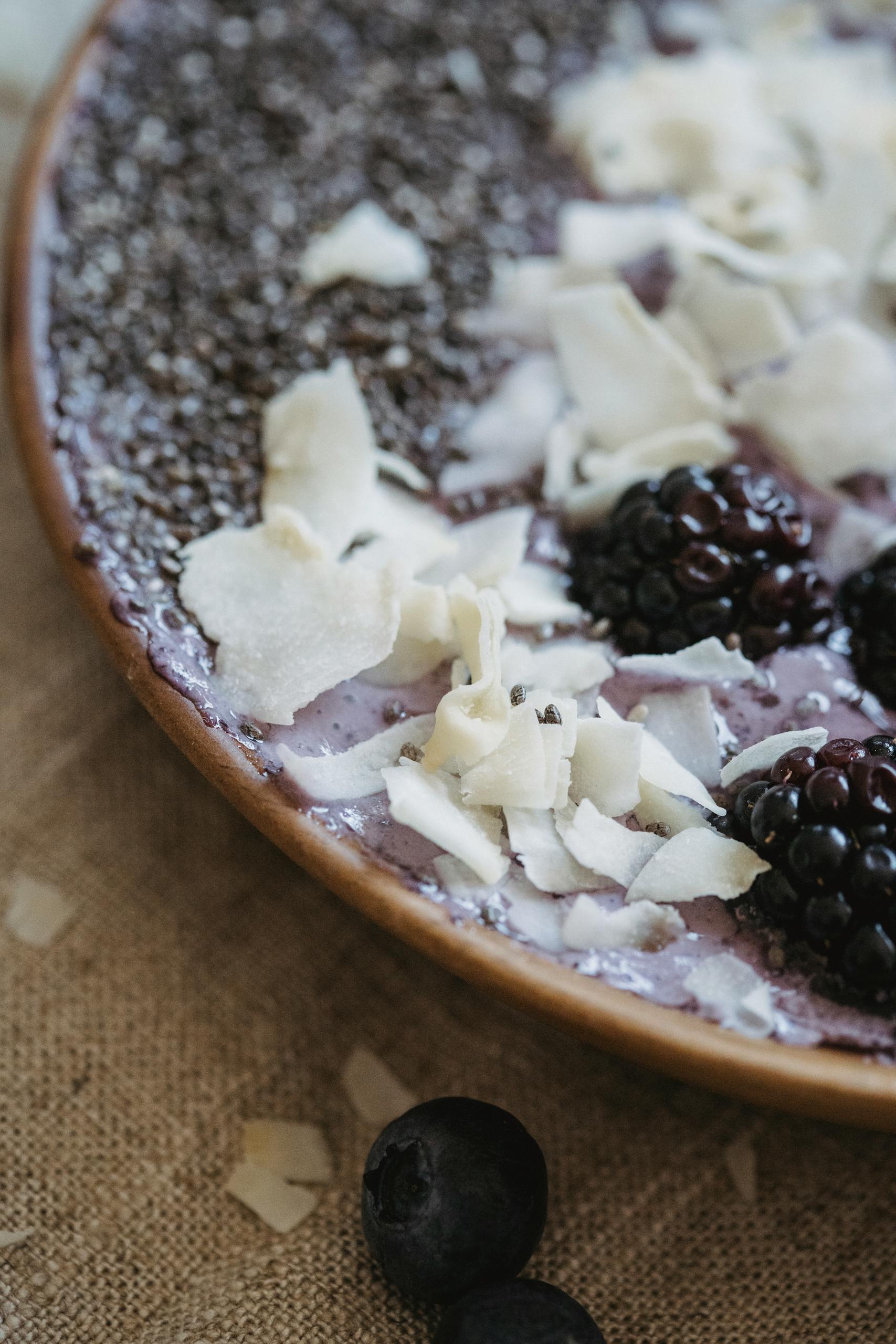 chia seeds for gut health benefits: Close-up of a breakfast bowl with blackberries, blueberries, chia, and coconut shavings.