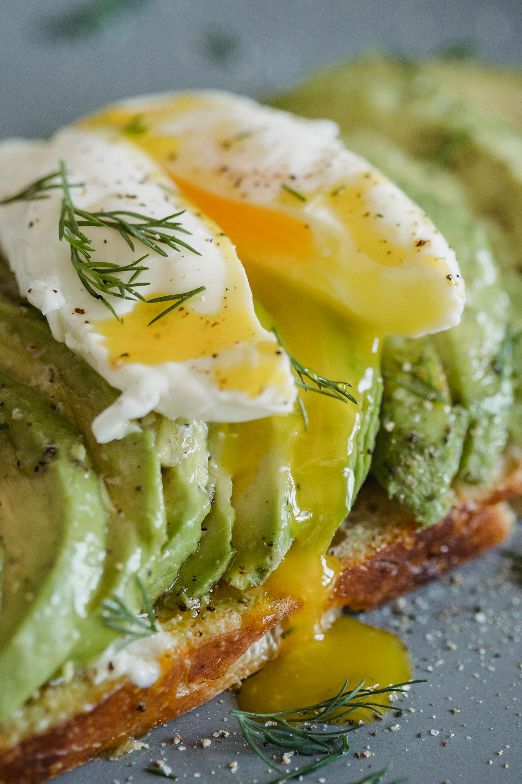 healthy breakfast ideas for busy mornings: Close-up of avocado toast topped with a perfectly poached egg and herbs.