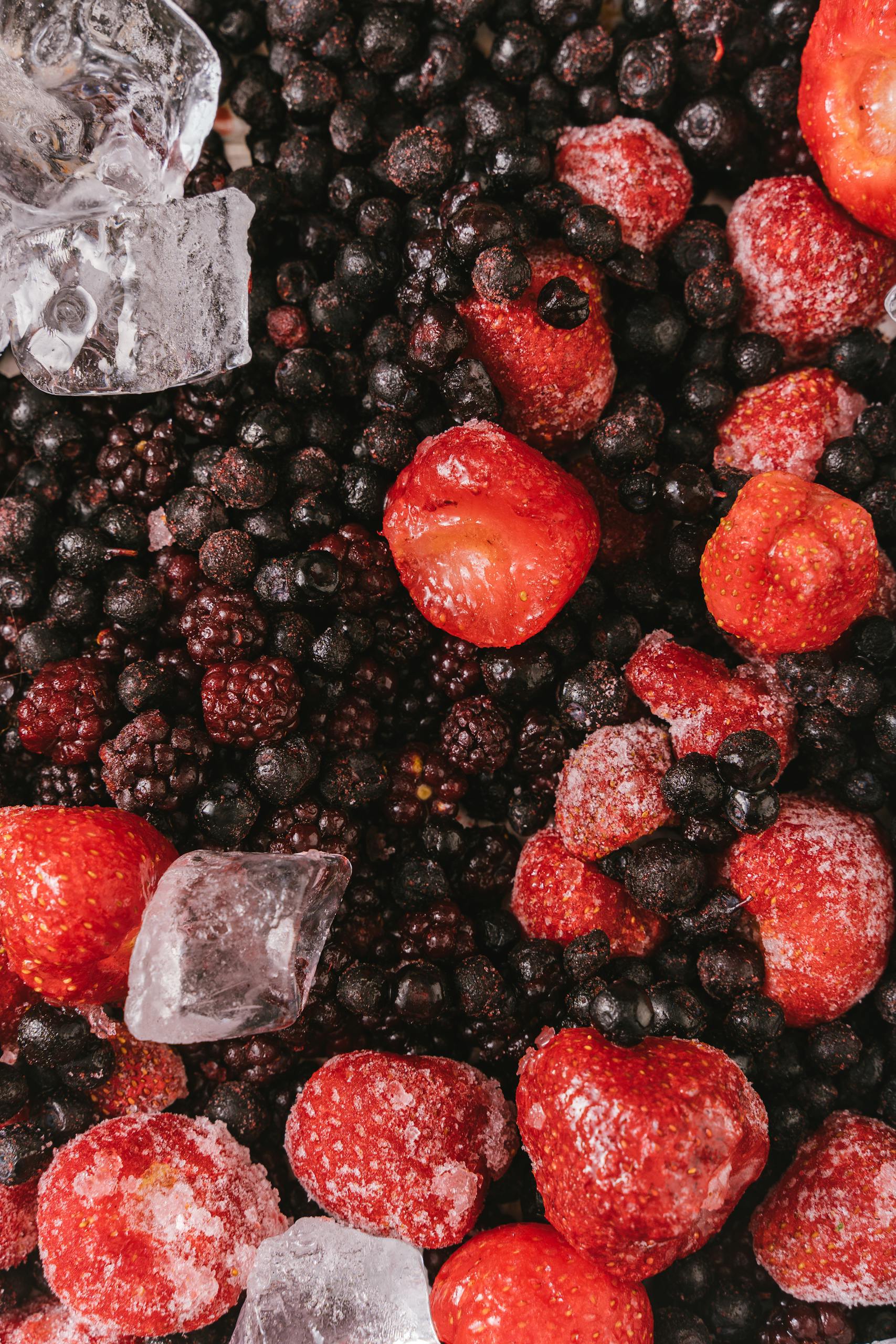 Healthiest Frozen Foods from Trader Joe's: Close-up of frozen strawberries, blackberries, and blueberries with ice cubes.