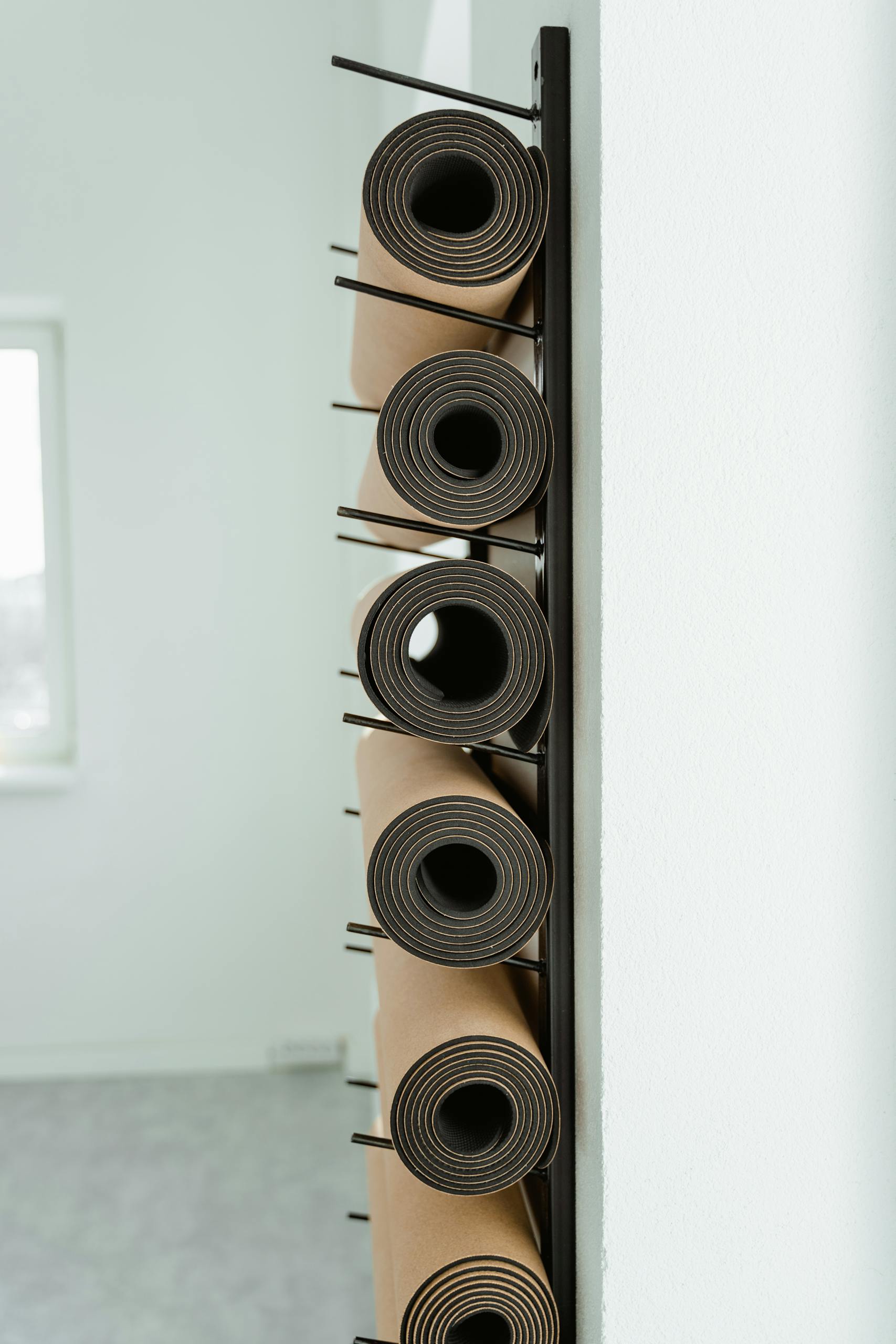 fasted cardio for fat loss: Close-up of neatly rolled yoga mats stored vertically on a rack in a studio.