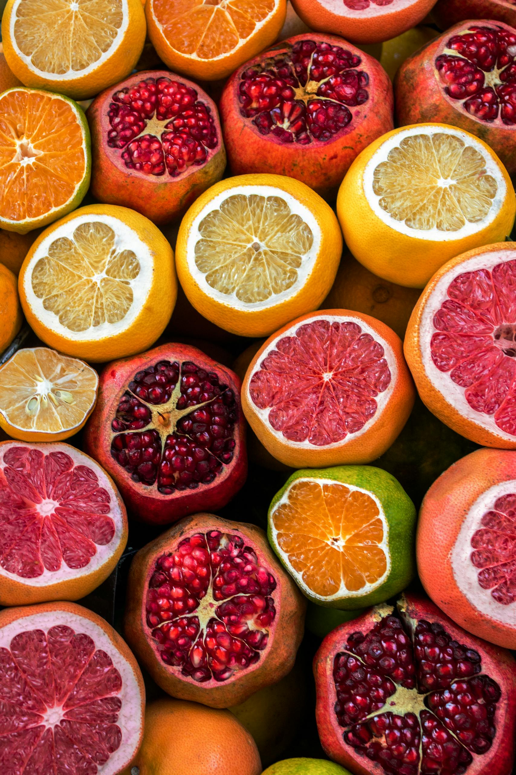 fibermaxxing: Colorful close-up of sliced citrus fruits and pomegranates in a vibrant arrangement, perfect for food enthusiasts.