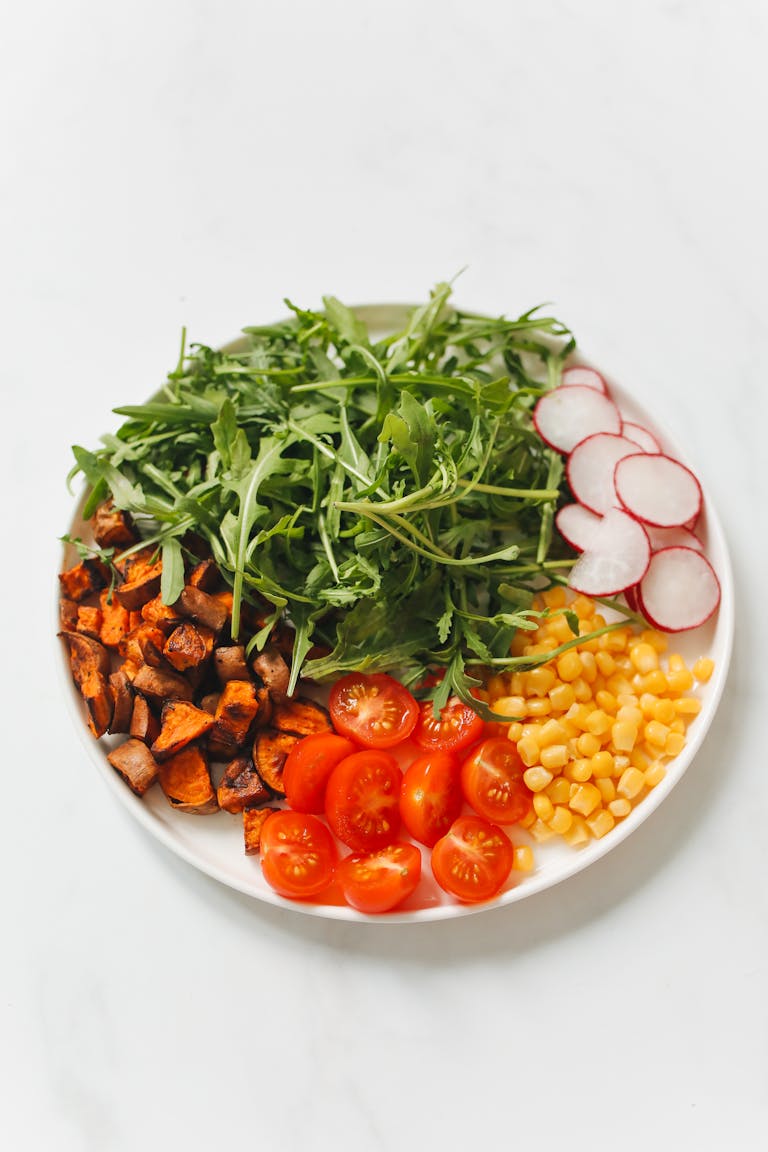 what does a balanced meal look like: Colorful vegetarian salad featuring arugula, cherry tomatoes, corn, radish, and sweet potatoes.