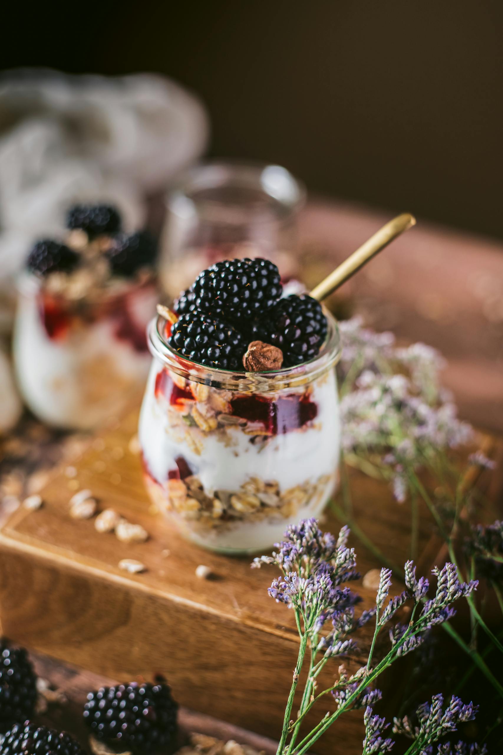 30 grams of fiber a day: Delicious blackberry and yogurt parfait with granola served in jars and decorated with flowers.