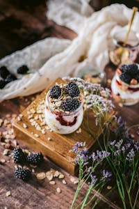 Greek yogurt vs. regular yogurt: Delicious blackberry yogurt parfait with granola and flowers in a rustic setting.