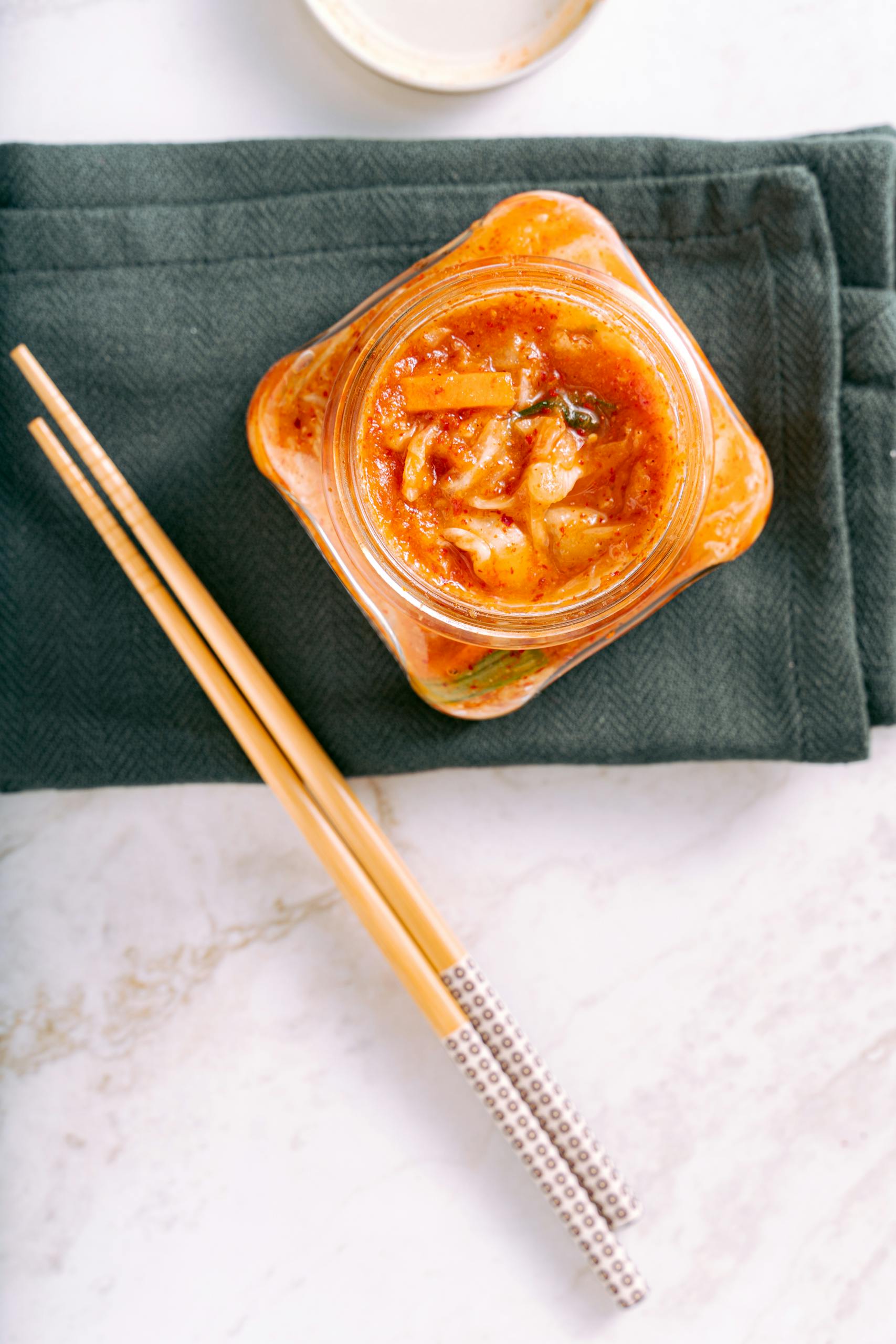 best probiotics for digestion: Delicious homemade kimchi in a glass jar with wooden chopsticks on a green napkin.
