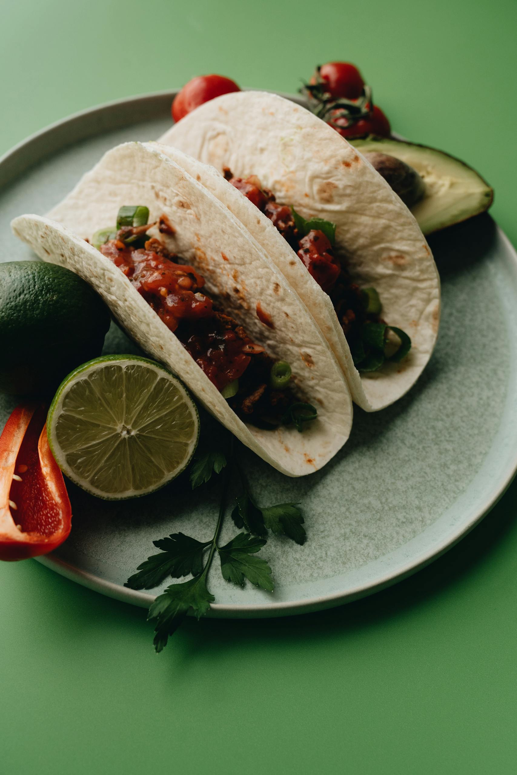 Corn Tortillas vs. Flour Tortillas: Delicious tacos with fresh avocado, lime, and peppers on a plate.