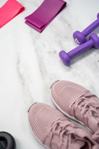 do GLP-1s cause muscle loss? Flat lay of pastel pink fitness gear including sneakers and dumbbells on marble texture.