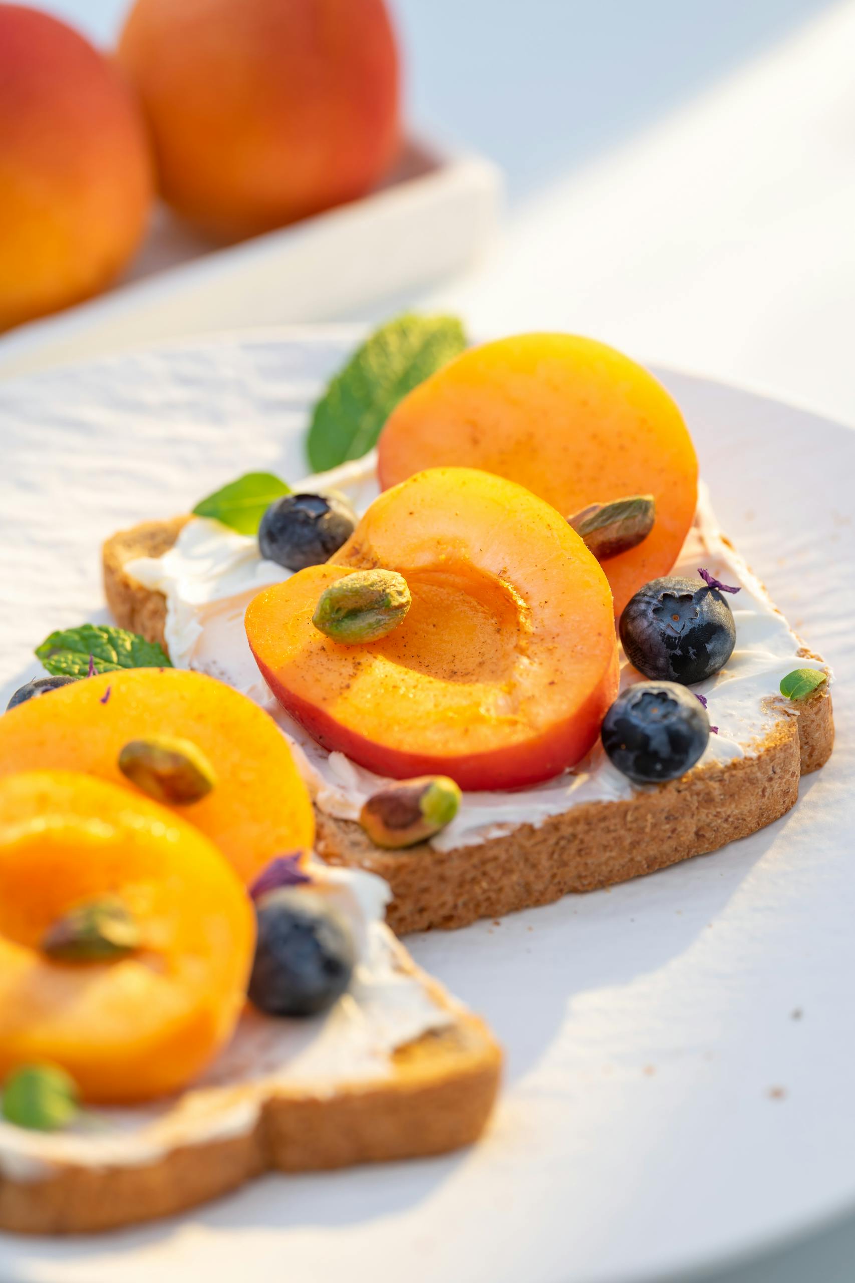 best healthy snacks at whole foods market: Fresh summer toast topped with juicy peaches, blueberries, and pistachios on a sunny day.
