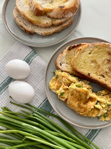 high-protein breakfast options at Target: Freshly made scrambled eggs with toast, perfect breakfast setup with ingredients like green onions and eggs.