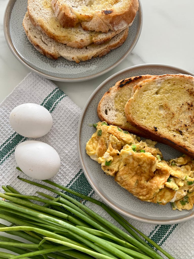 high-protein breakfast options at Target: Freshly made scrambled eggs with toast, perfect breakfast setup with ingredients like green onions and eggs.