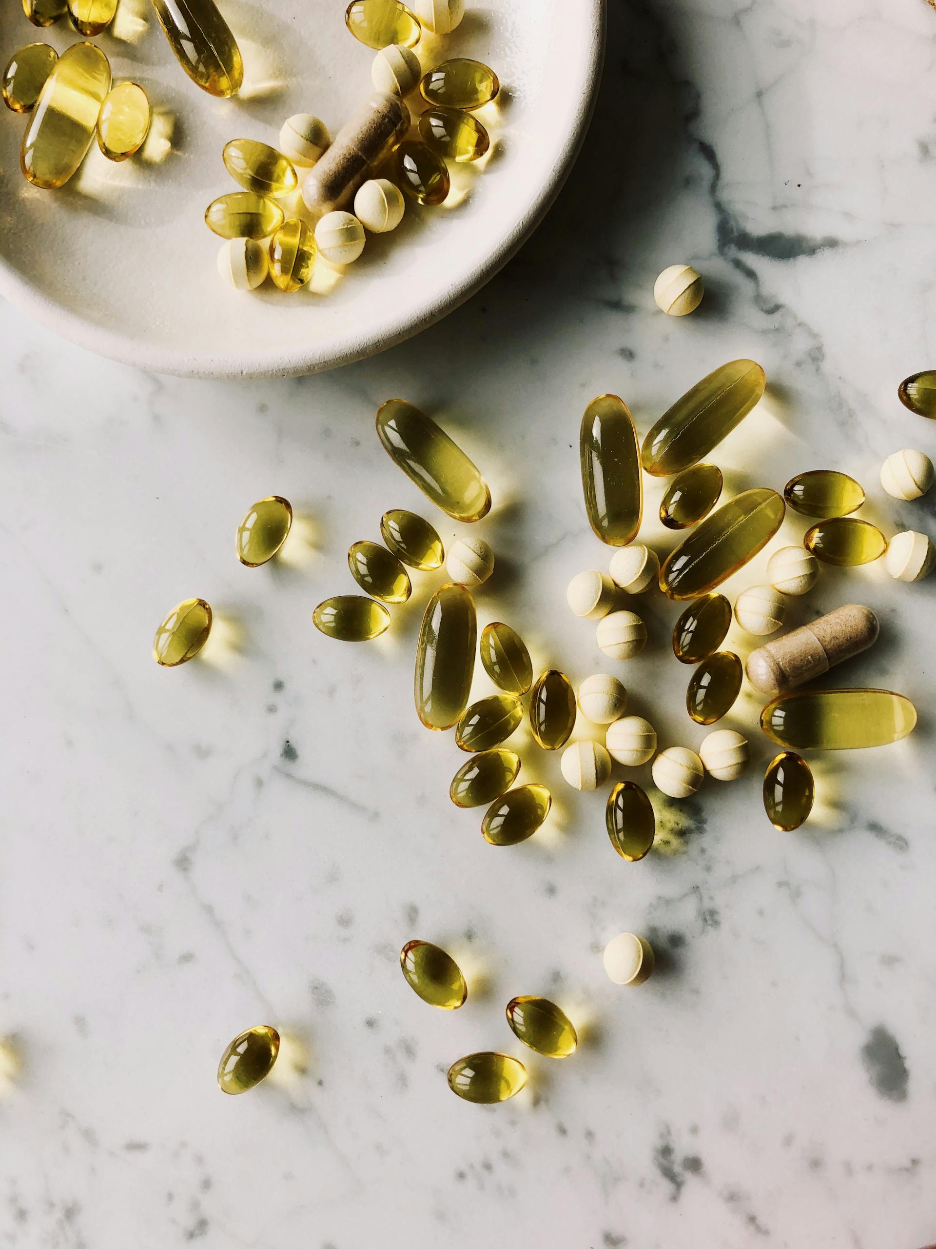 best probiotics for digestion: Scattered vitamins and supplements on a marble surface, highlighting healthcare and wellness.