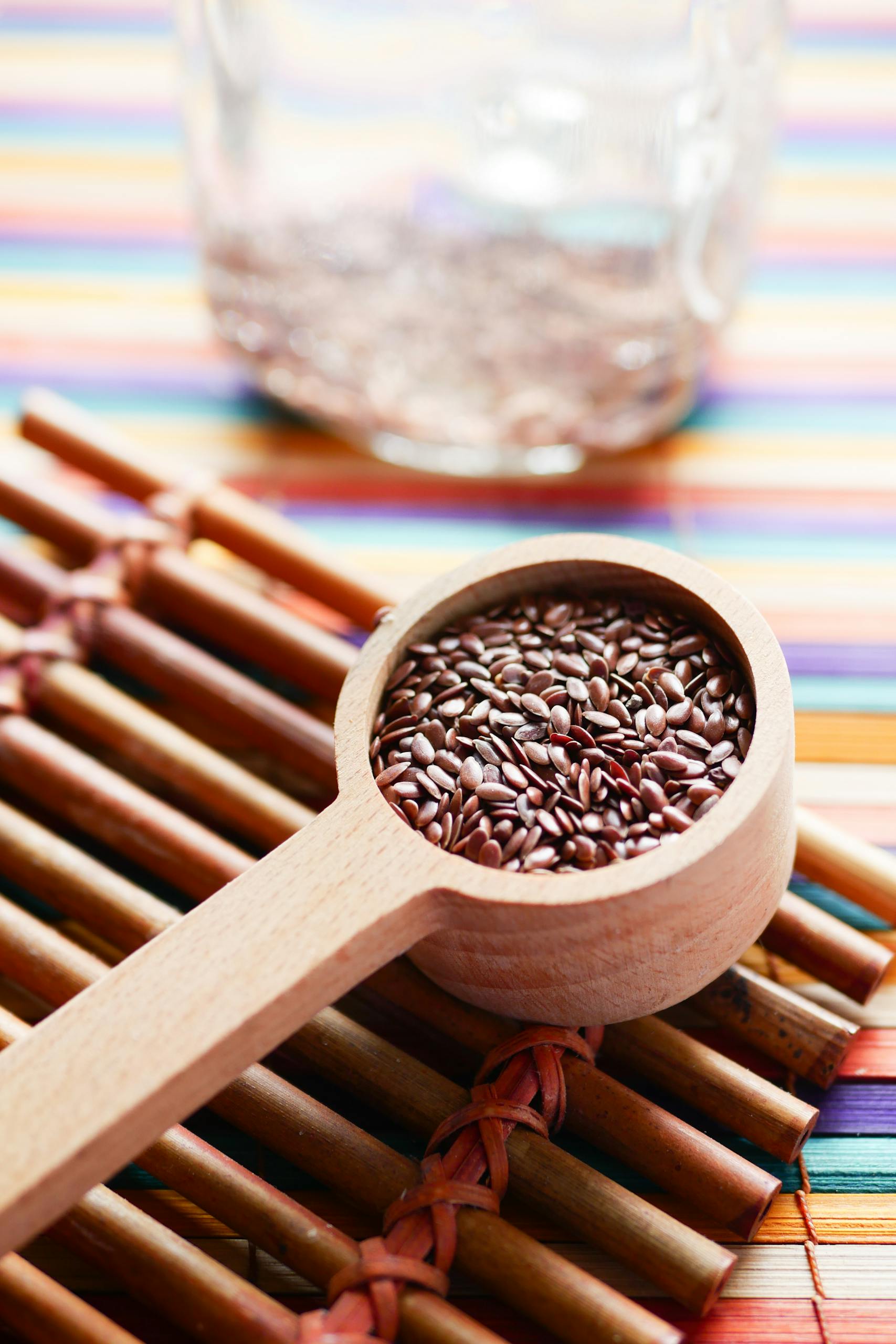 flaxseed benefits: Vibrant close-up of flaxseeds in a wooden spoon on a colorful mat promoting healthy eating.