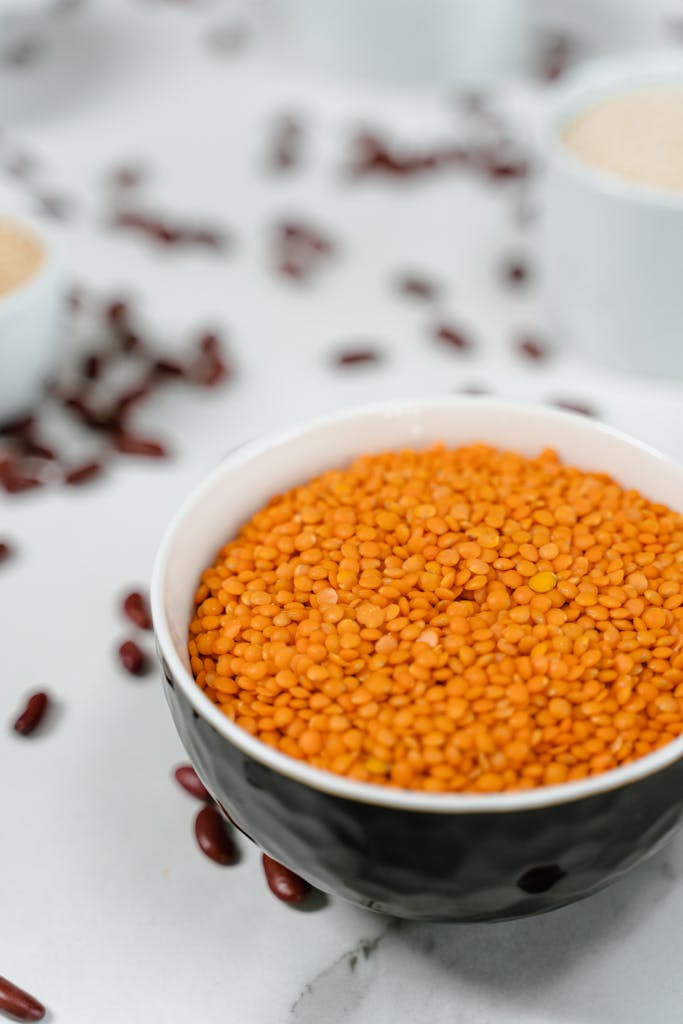 zinc and hormones: A close-up view of raw red lentils in a ceramic bowl on a kitchen counter.