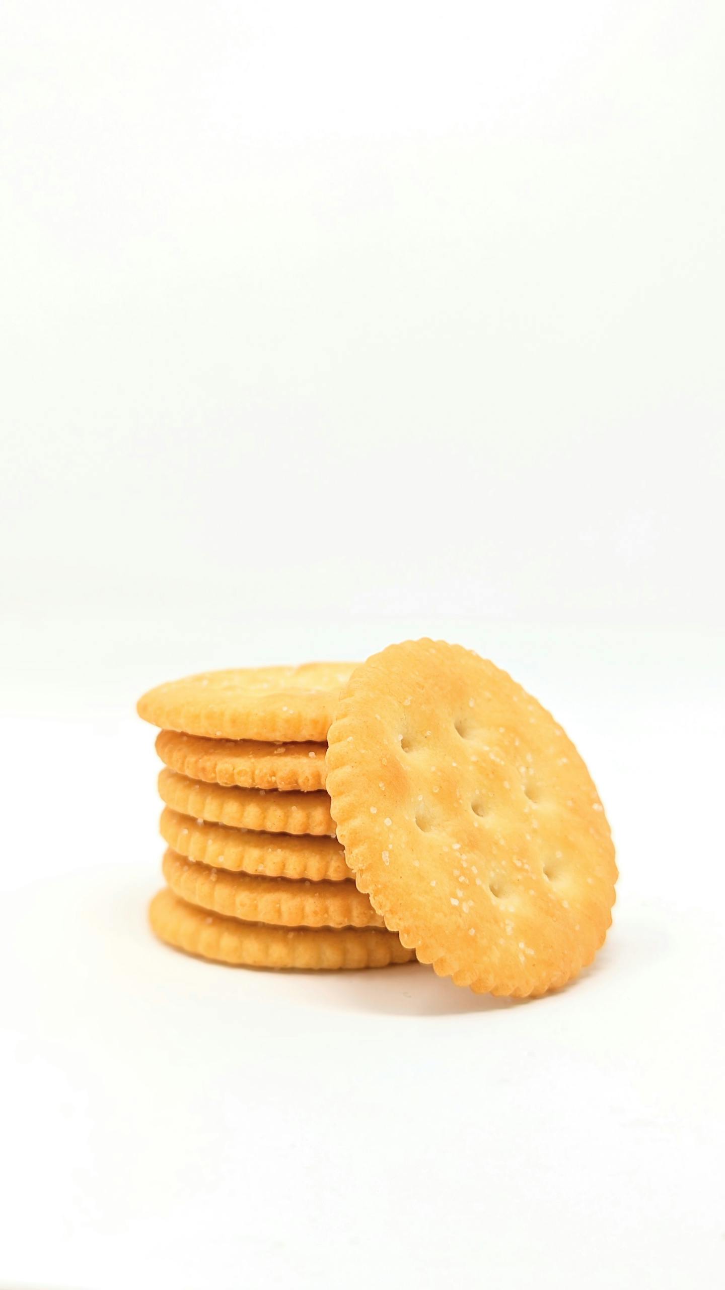 Are Ultra-Processed Foods Always Unhealthy: A stack of golden round crackers on a plain white surface, perfect for snack time.