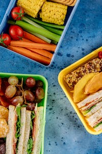 Body recomposition meal plan for beginners: A vibrant flat lay of healthy lunch boxes featuring sandwiches, fruits, and vegetables, perfect for a nutritious meal.