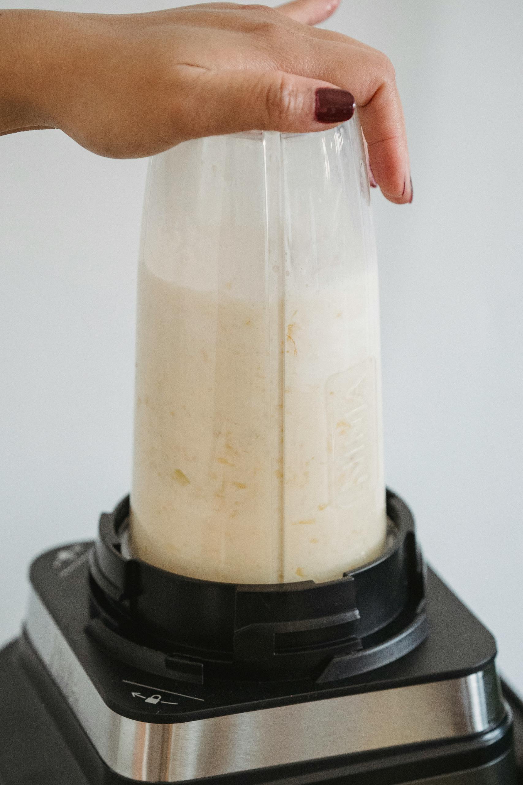 Best Post-Workout Meals for Muscle Recovery: Close-up of a hand blending a smoothie in a sleek blender, highlighting food preparation.